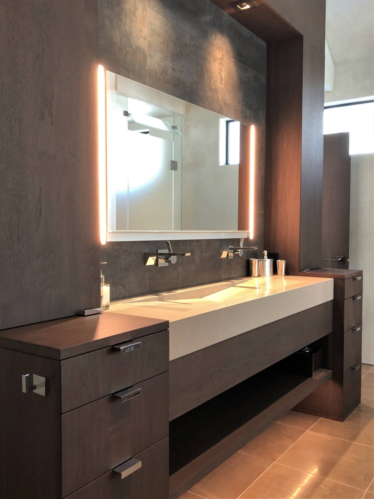 Mid-sized trendy master gray tile brown floor and double-sink bathroom with flat-panel cabinets, dark wood cabinets, beige walls, a trough sink, a hinged shower door, beige countertops and a built-in vanity, by Jensen Design in Telluride, CO