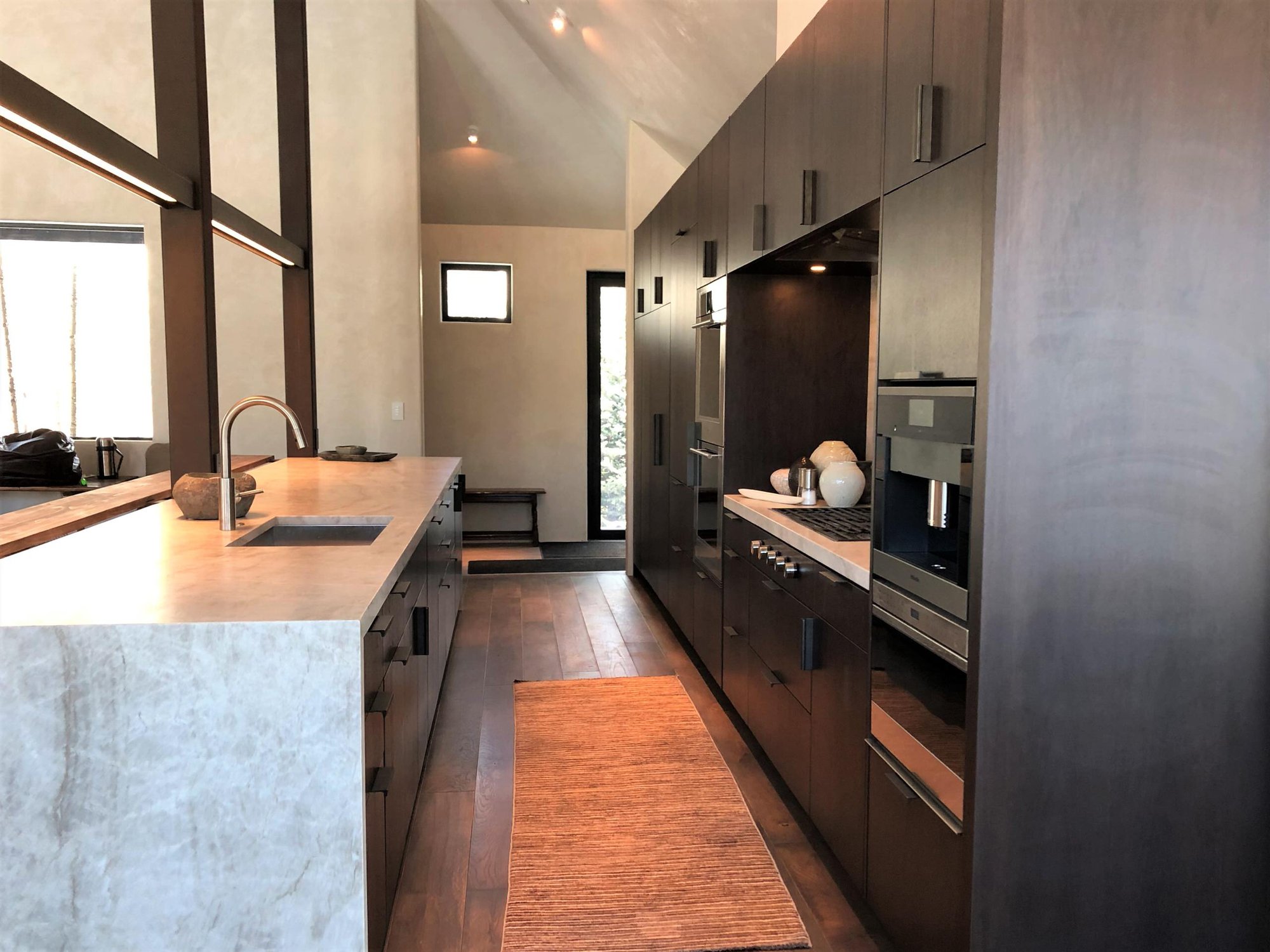 Large contemporary galley medium tone wood floor, brown floor and vaulted ceiling open concept kitchen with an undermount sink, flat-panel cabinets, dark wood cabinets, colored appliances, an island and multicolored countertops, by Jensen Design in Telluride, CO