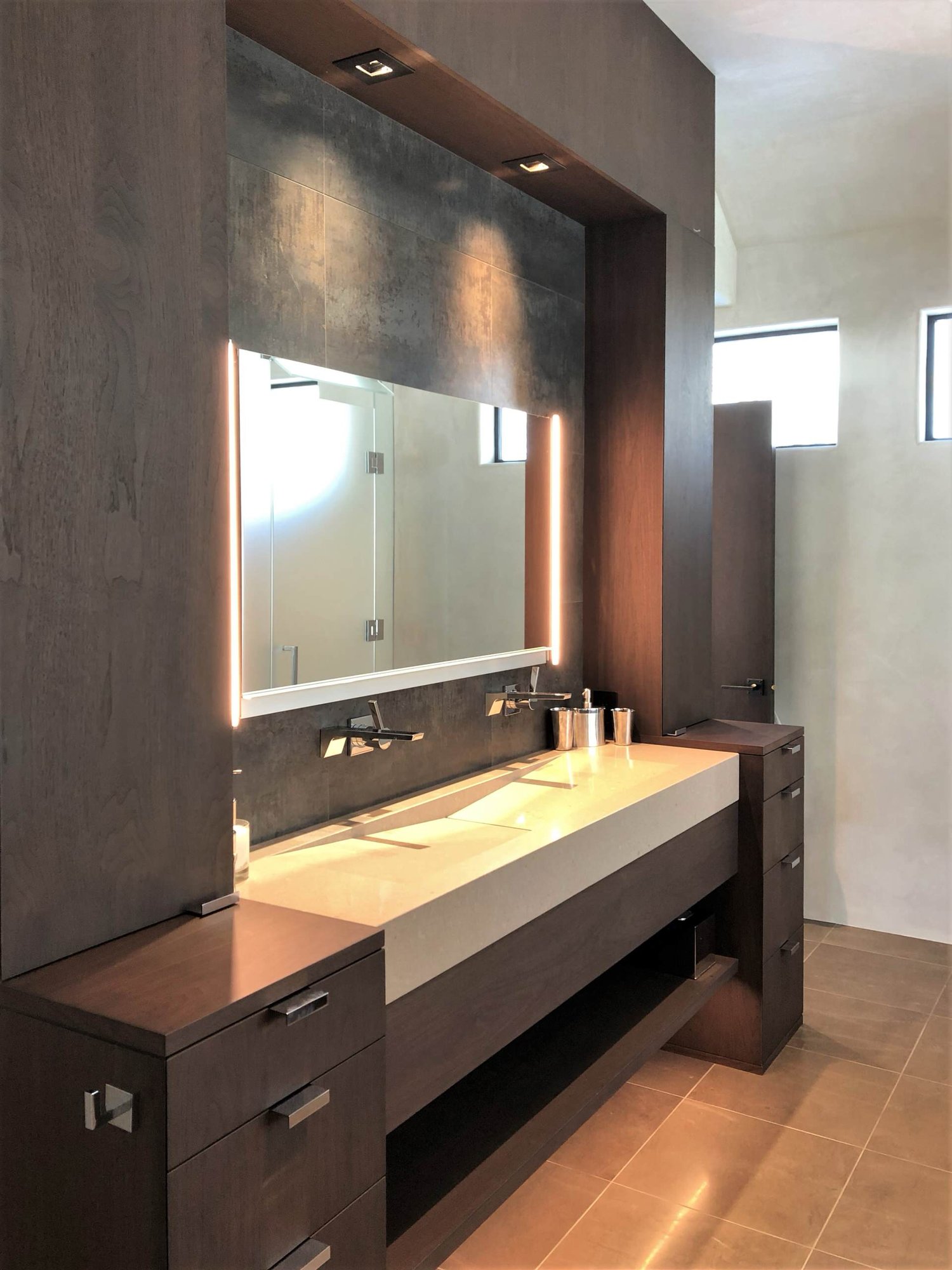 Mid-sized trendy master gray tile brown floor and double-sink bathroom with flat-panel cabinets, dark wood cabinets, beige walls, a trough sink, a hinged shower door, beige countertops and a built-in vanity, by Jensen Design in Telluride, CO