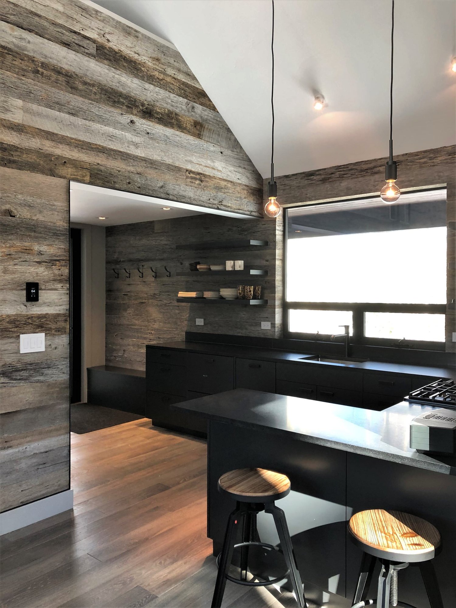 Mid-sized trendy u-shaped light wood floor, orange floor and vaulted ceiling open concept kitchen with an undermount sink, flat-panel cabinets, black cabinets, brown backsplash, stainless steel appliances, a peninsula and brown countertops, by Jensen Design in Telluride, CO