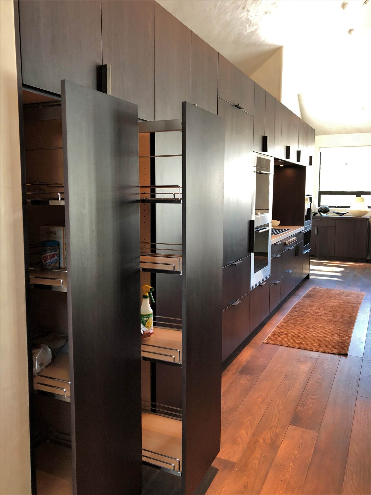 Large contemporary galley medium tone wood floor, brown floor and vaulted ceiling open concept kitchen with an undermount sink, flat-panel cabinets, dark wood cabinets, colored appliances, an island and multicolored countertops, by Jensen Design in Telluride, CO