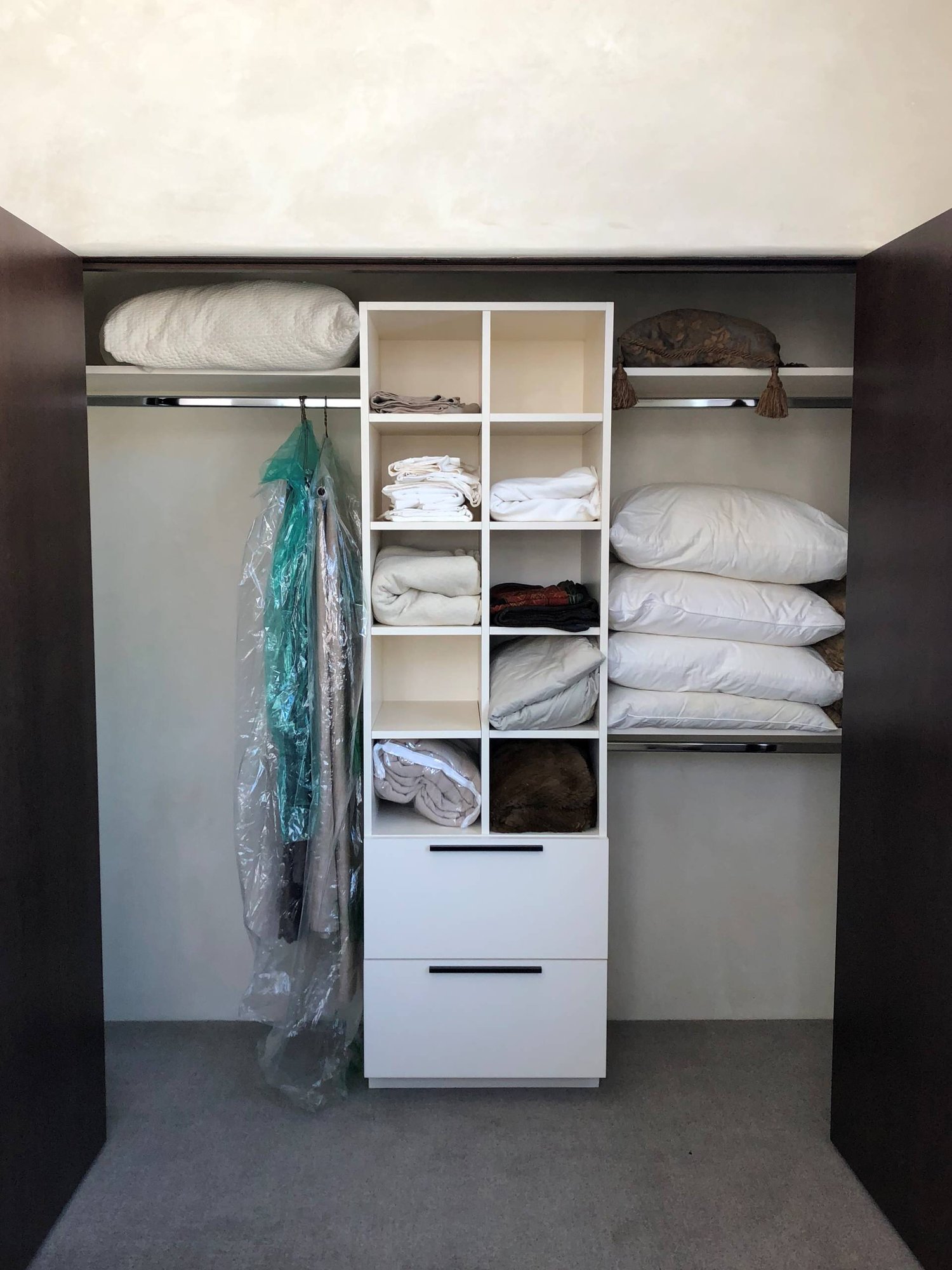 Small trendy gender-neutral carpeted and gray floor reach-in closet with flat-panel cabinets and white cabinets, by Jensen Design in Telluride, CO