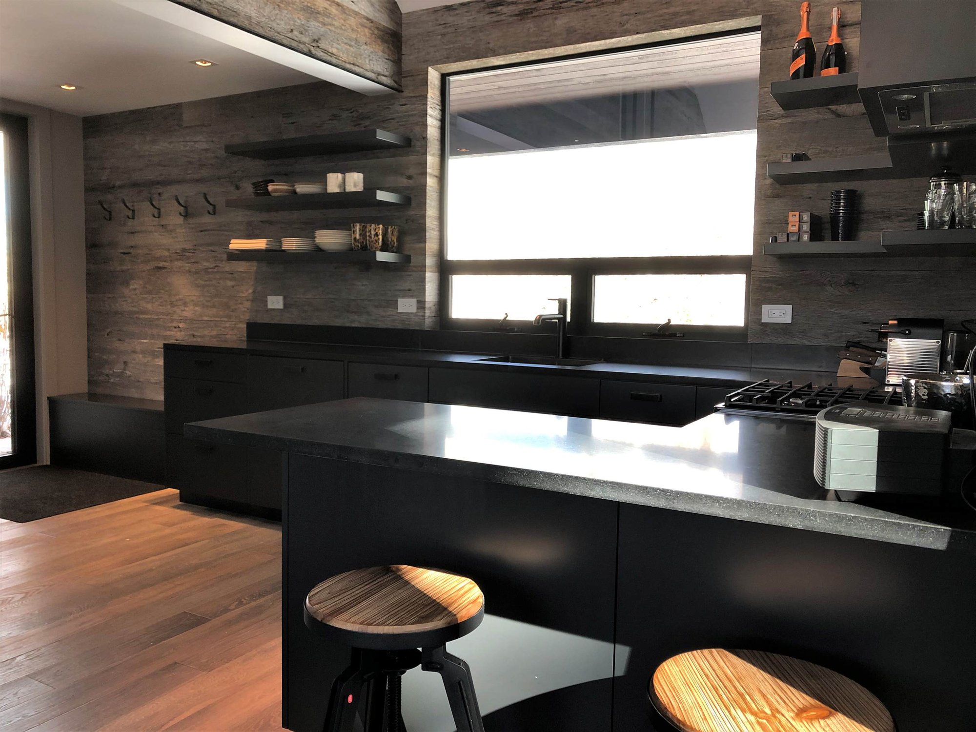 Mid-sized contemporary u-shaped light wood floor, orange floor and vaulted ceiling open concept kitchen with an undermount sink, flat-panel cabinets, black cabinets, brown backsplash, stainless steel appliances, a peninsula and brown countertops, by Jensen Design in Telluride, CO