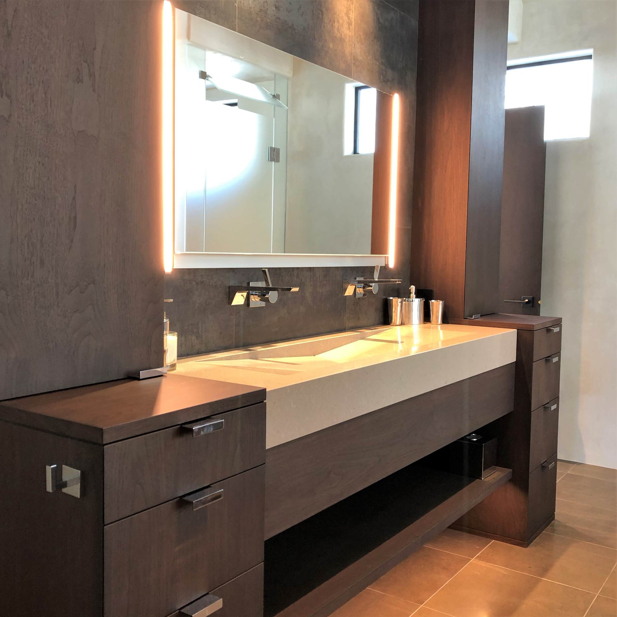 Mid-sized trendy master gray tile brown floor and double-sink bathroom with flat-panel cabinets, dark wood cabinets, beige walls, a trough sink, a hinged shower door, beige countertops and a built-in vanity, by Jensen Design in Telluride, CO