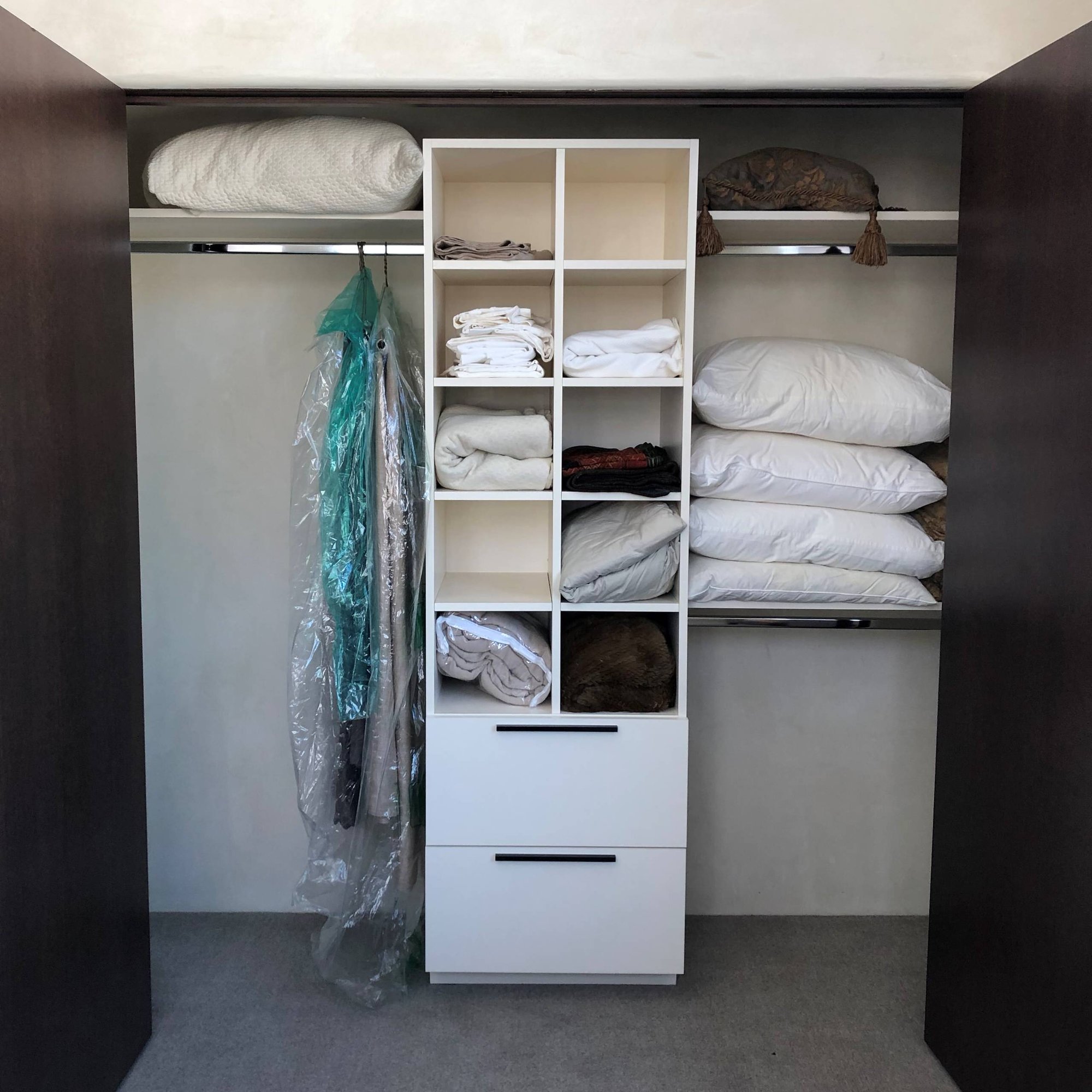 Small trendy gender-neutral carpeted and gray floor reach-in closet with flat-panel cabinets and white cabinets, by Jensen Design in Telluride, CO