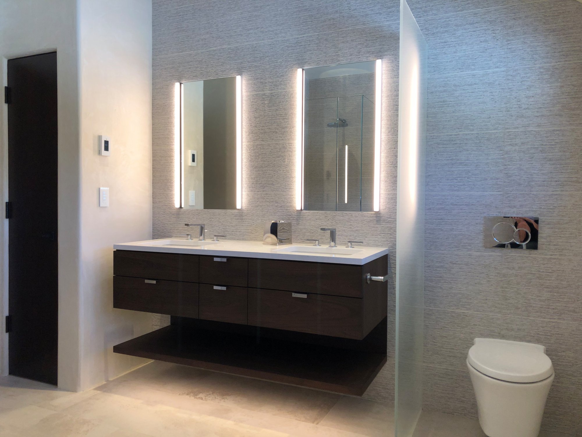 Mid-sized trendy master gray tile beige floor, double-sink and vaulted ceiling bathroom with flat-panel cabinets, dark wood cabinets, gray walls, an undermount sink, white countertops and a floating vanity, by Jensen Design in Telluride, CO