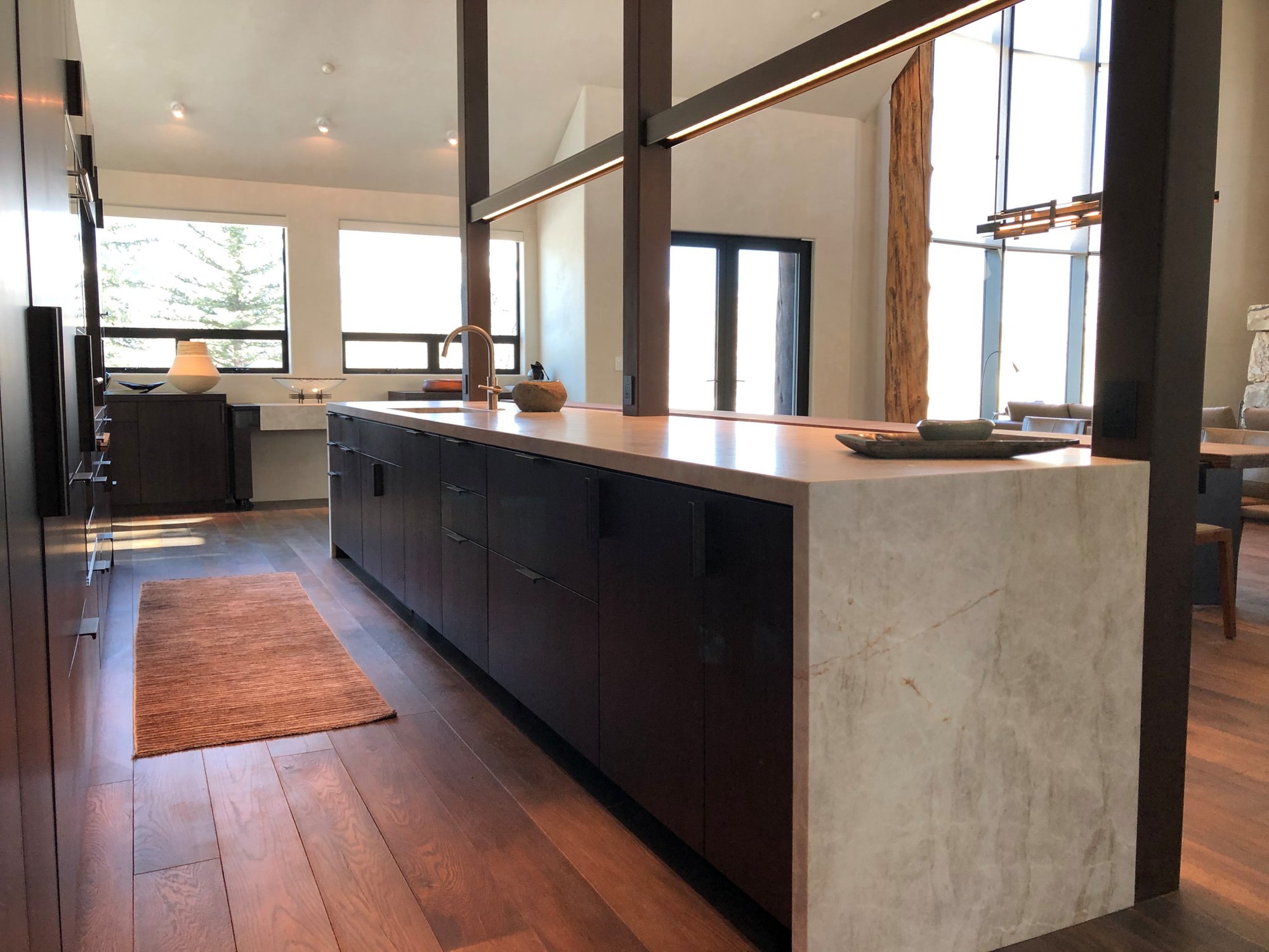 Large trendy galley medium tone wood floor, brown floor and vaulted ceiling open concept kitchen with an undermount sink, flat-panel cabinets, dark wood cabinets, colored appliances, an island and multicolored countertops, by Jensen Design in Telluride, CO