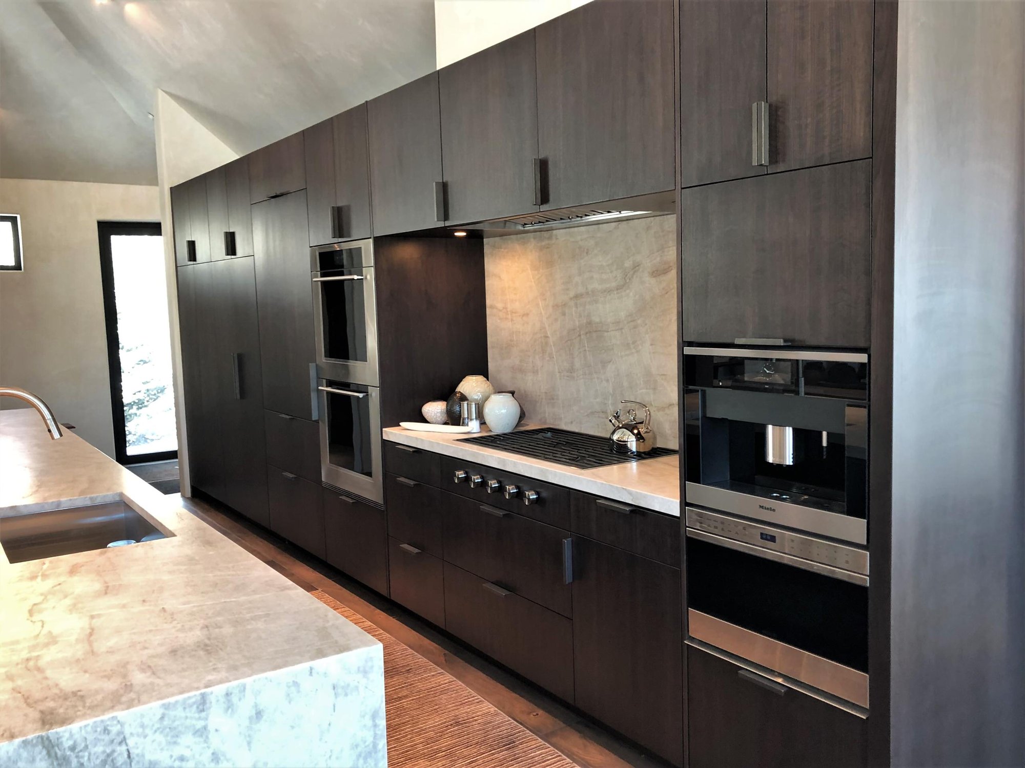 Large trendy galley medium tone wood floor, brown floor and vaulted ceiling open concept kitchen with an undermount sink, flat-panel cabinets, dark wood cabinets, colored appliances, an island and multicolored countertops, by Jensen Design in Telluride, CO