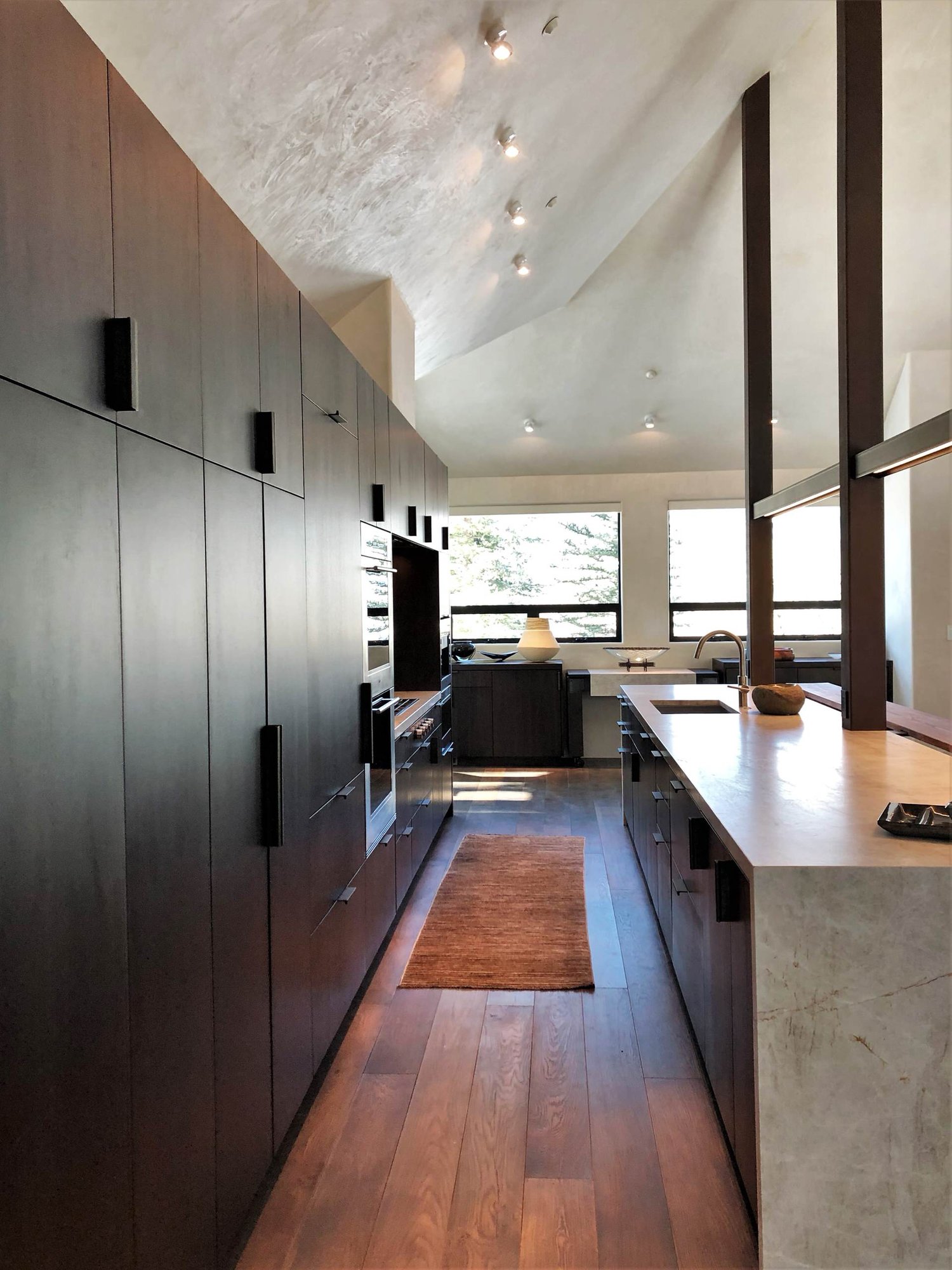 Large contemporary galley medium tone wood floor, brown floor and vaulted ceiling open concept kitchen with an undermount sink, flat-panel cabinets, dark wood cabinets, colored appliances, an island and multicolored countertops, by Jensen Design in Telluride, CO