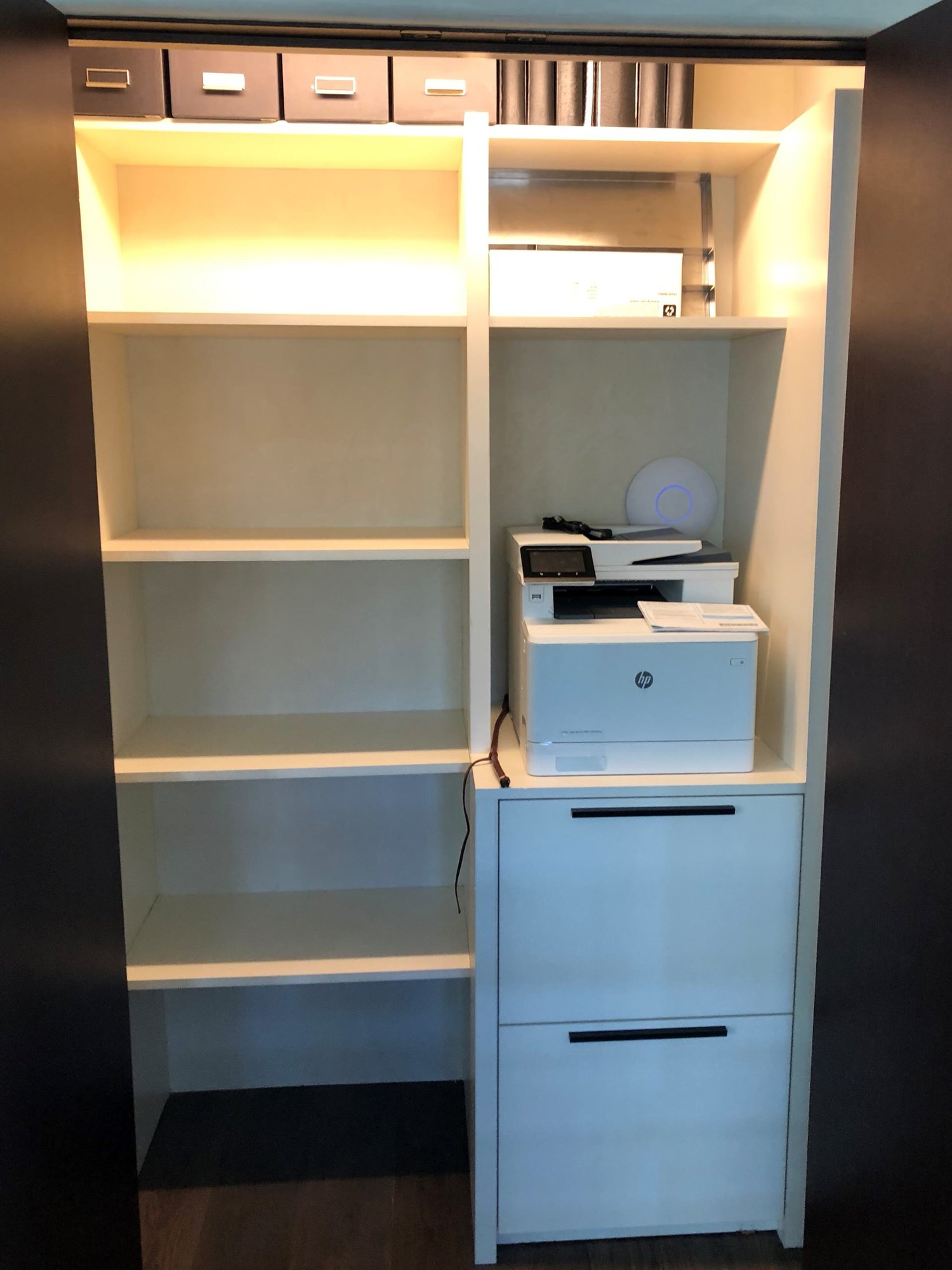 Small trendy gender-neutral medium tone wood floor and gray floor reach-in closet with flat-panel cabinets and white cabinets, by Jensen Design in Telluride, CO
