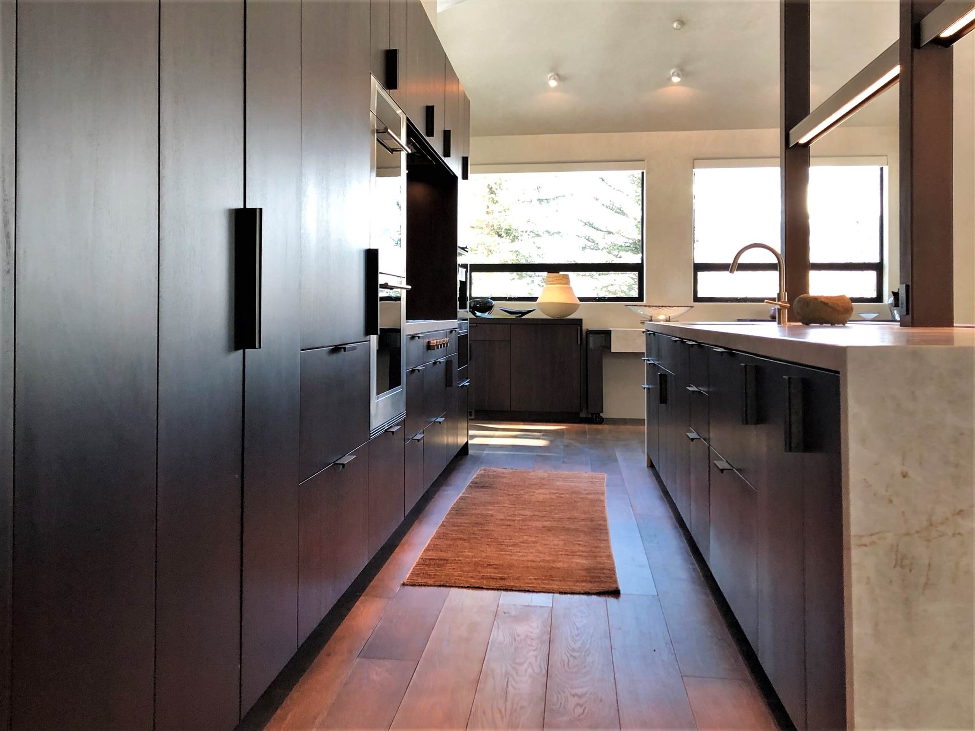 Large contemporary galley medium tone wood floor, brown floor and vaulted ceiling open concept kitchen with an undermount sink, flat-panel cabinets, dark wood cabinets, colored appliances, an island and multicolored countertops, by Jensen Design in Telluride, CO