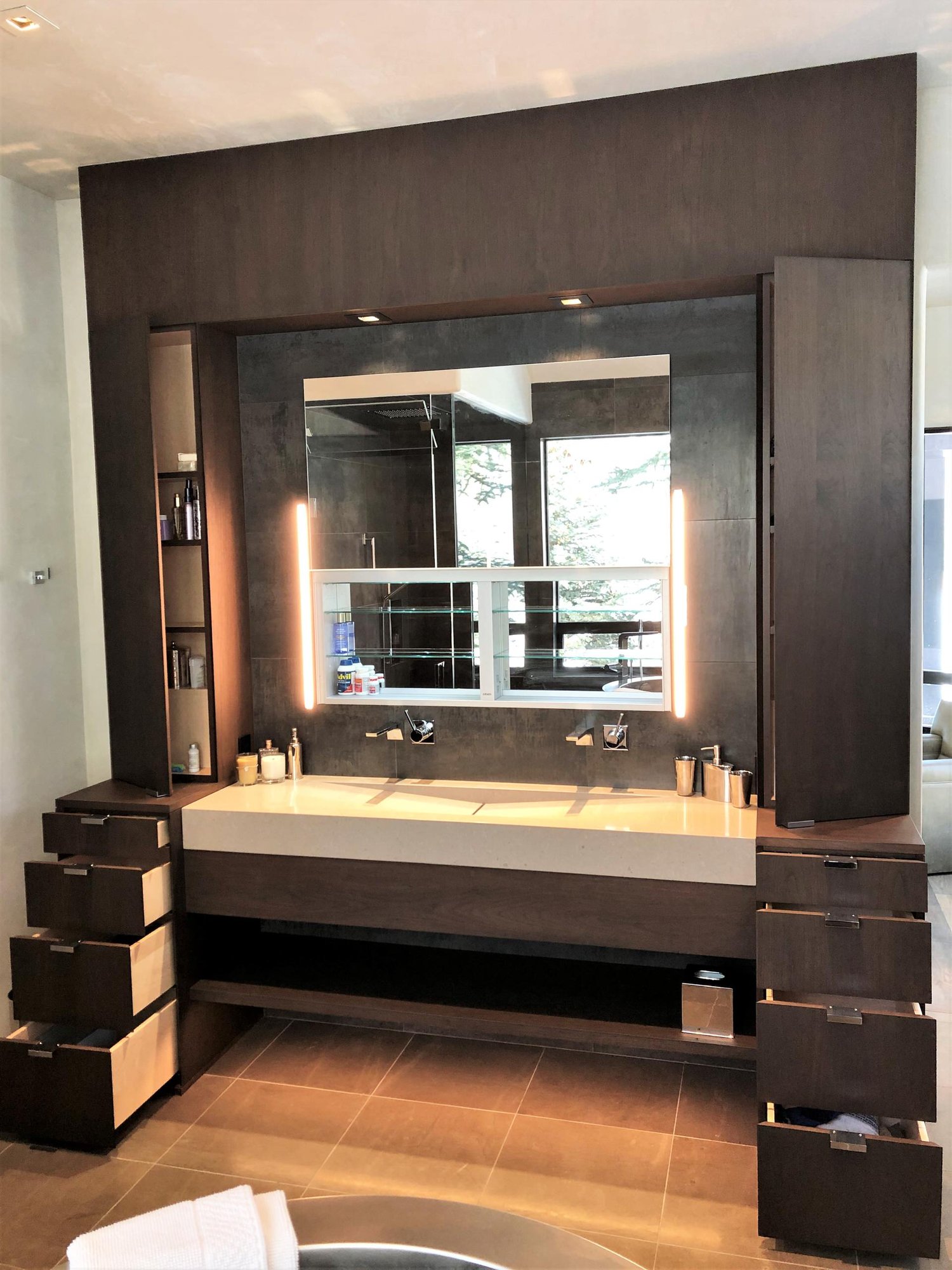 Mid-sized contemporary master gray tile brown floor and double-sink bathroom with flat-panel cabinets, dark wood cabinets, beige walls, a trough sink, a hinged shower door, beige countertops and a built-in vanity, by Jensen Design in Telluride, CO