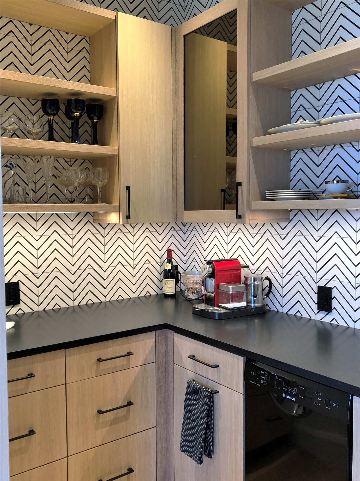 Mid-sized contemporary u-shaped medium tone wood floor and brown floor kitchen pantry with an undermount sink, flat-panel cabinets, light wood cabinets, white backsplash, black appliances and black countertops, by Jensen Design in Telluride, CO