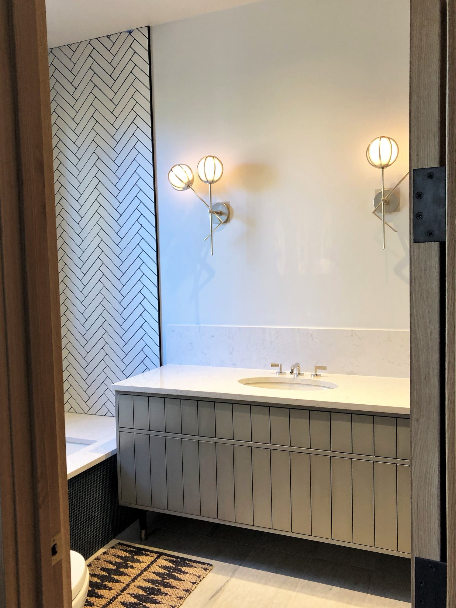 Mid-sized contemporary kids' white tile single-sink drop-in bathtub with flat-panel cabinets, gray cabinets, white walls, an undermount sink, beige countertops and a freestanding vanity, by Jensen Design in Telluride, CO