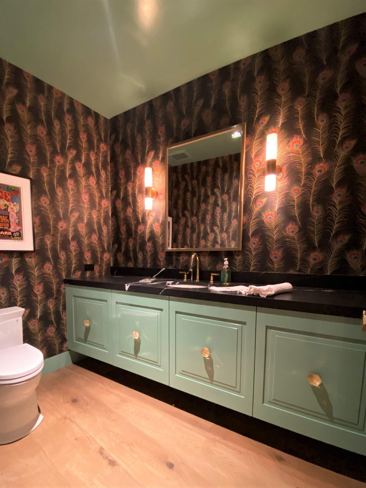 Mid-sized eclectic 3/4 light wood floor, brown floor, single-sink and wallpaper bathroom with raised-panel cabinets, green cabinets, a two-piece toilet, an undermount sink, black countertops and a floating vanity, by Jensen Design in Telluride, CO