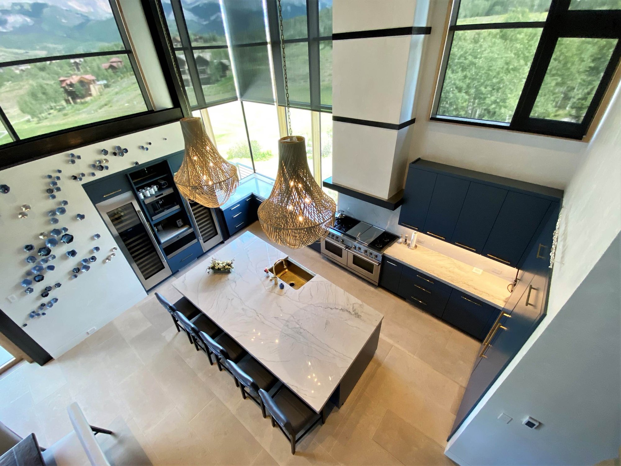 Large trendy u-shaped limestone floor, gray floor and wood ceiling open concept kitchen with a farmhouse sink, flat-panel cabinets, blue cabinets, marble countertops, white backsplash, marble backsplash, paneled appliances, an island and white countertops, by Jensen Design in Telluride, CO