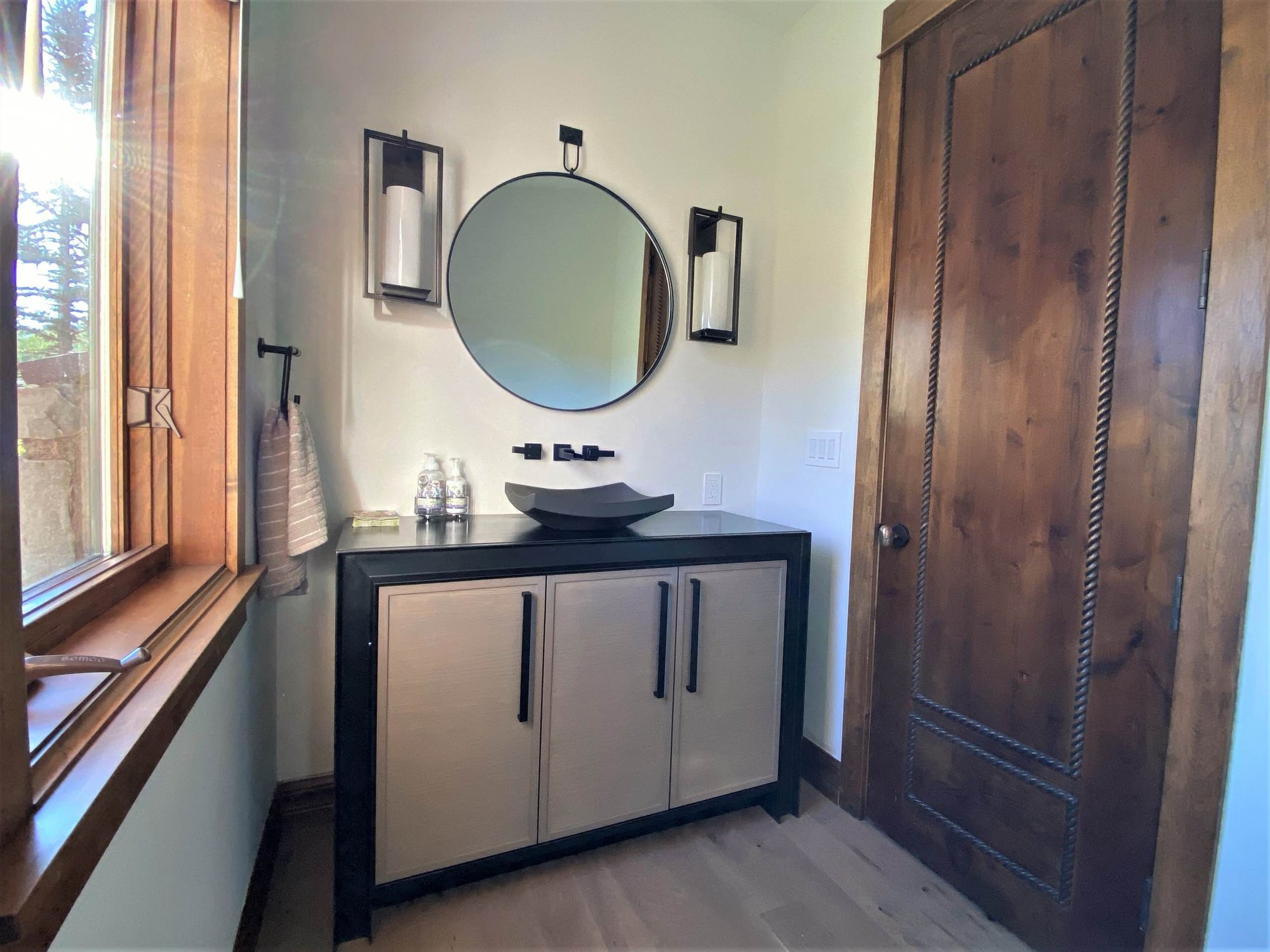 Small transitional 3/4 single-sink bathroom with recessed-panel cabinets, medium tone wood cabinets, black countertops and a freestanding vanity, by Jensen Design in Telluride, CO