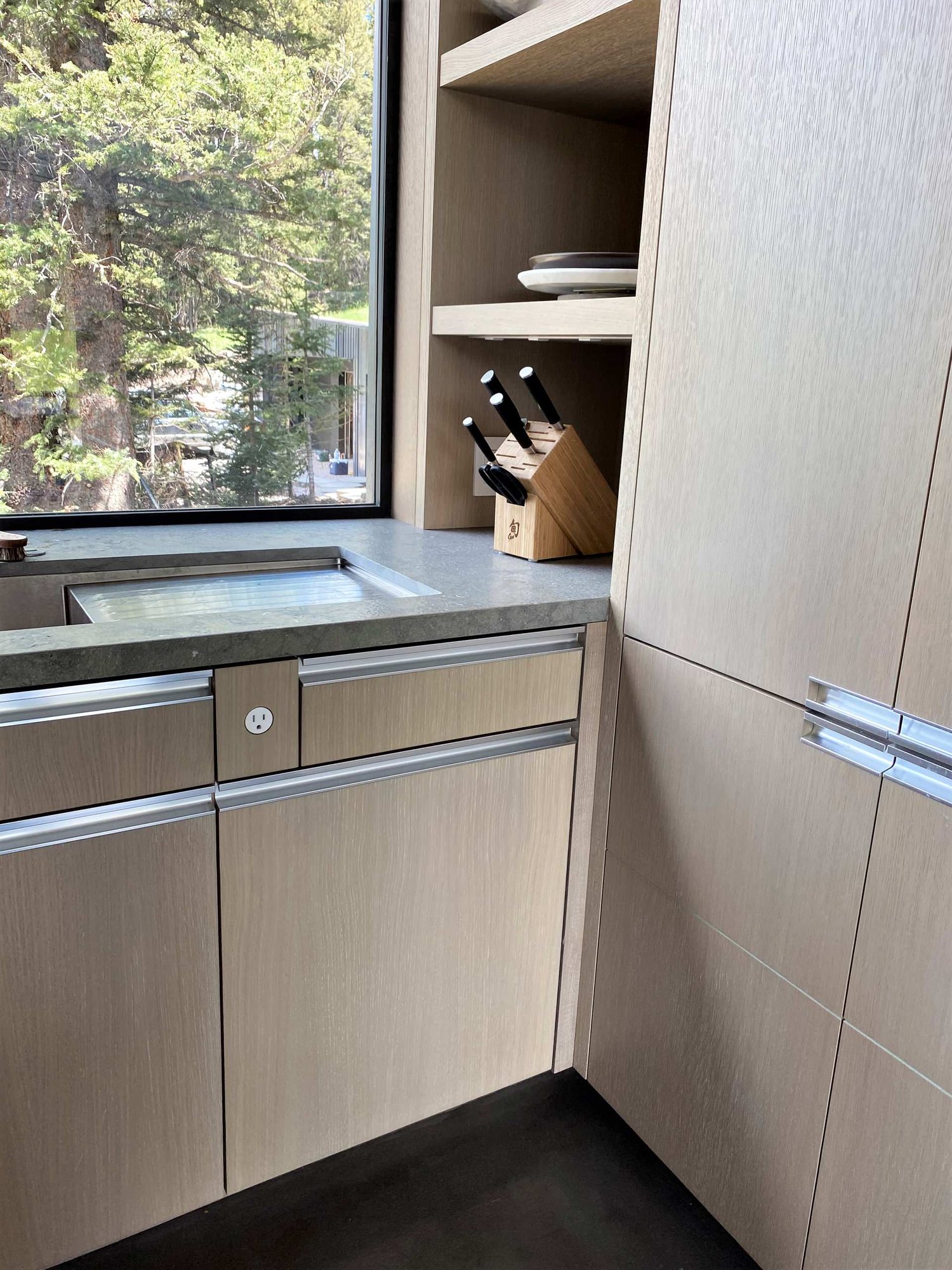 Large contemporary u-shaped concrete floor, gray floor and wood ceiling open concept kitchen with an undermount sink, flat-panel cabinets, light wood cabinets, yellow backsplash, glass sheet backsplash, paneled appliances, an island and gray countertops, by Jensen Design in Telluride, CO