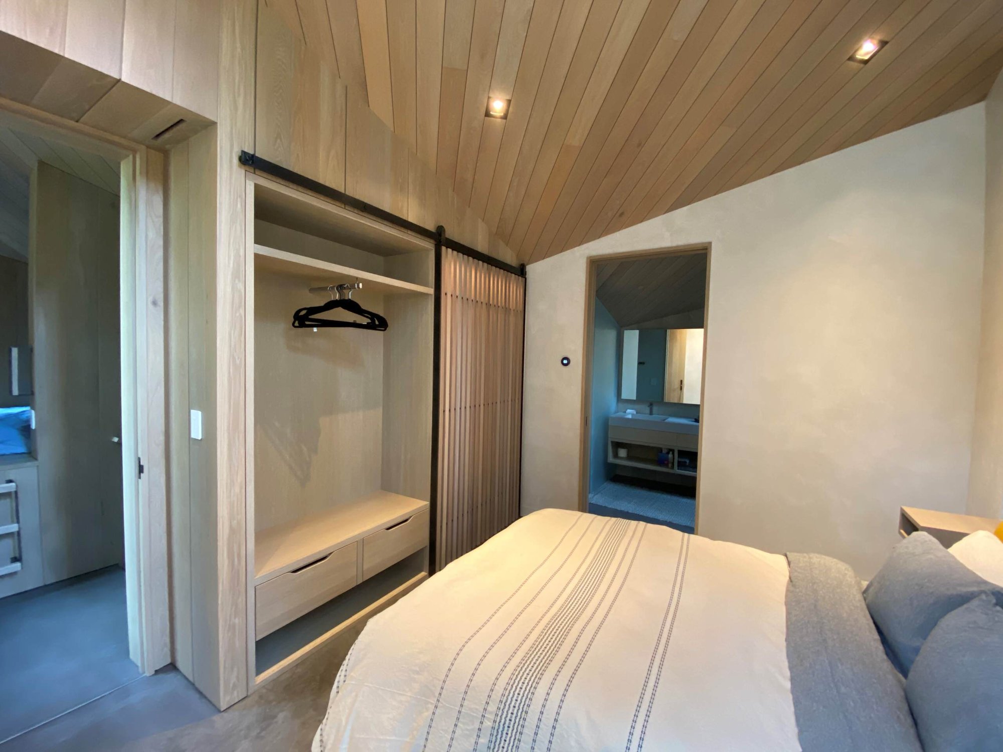 Mid-sized contemporary guest concrete floor, gray floor, wood ceiling and wood wall bedroom with beige walls, by Jensen Design in Telluride, CO