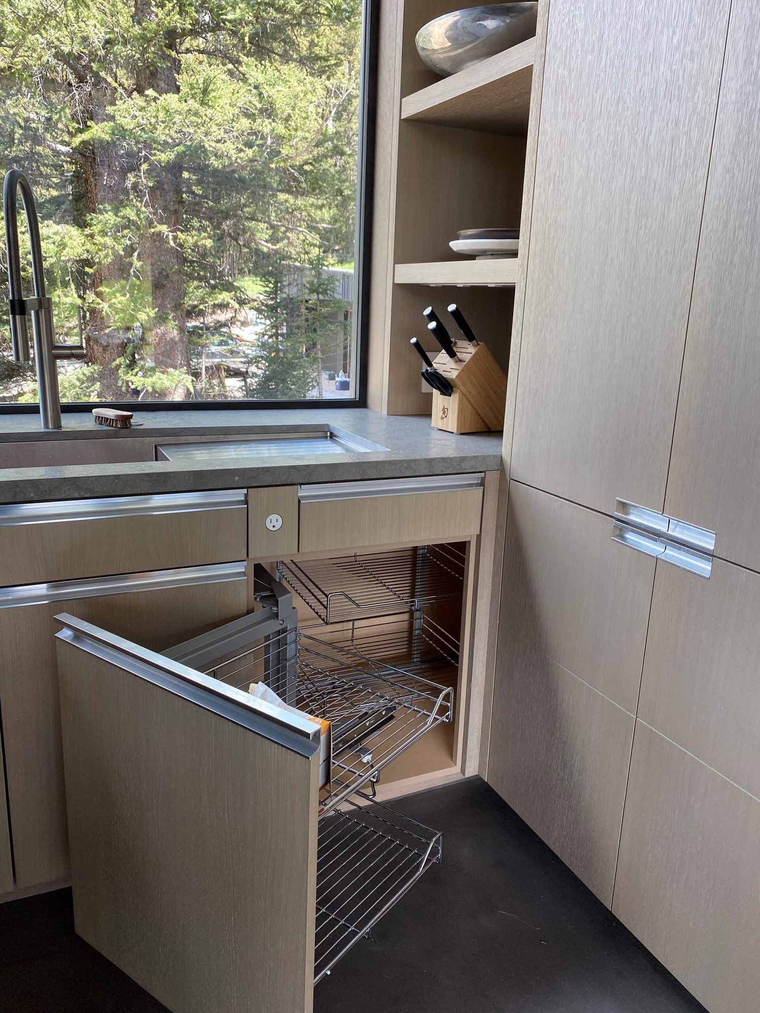 Large contemporary u-shaped concrete floor, gray floor and wood ceiling open concept kitchen with an undermount sink, flat-panel cabinets, light wood cabinets, yellow backsplash, glass sheet backsplash, paneled appliances, an island and gray countertops, by Jensen Design in Telluride, CO