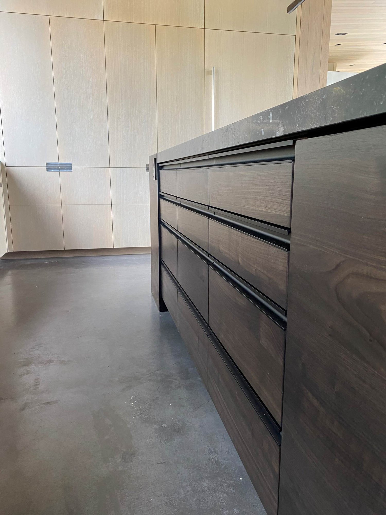 Large contemporary u-shaped concrete floor, gray floor and wood ceiling open concept kitchen with an undermount sink, flat-panel cabinets, light wood cabinets, yellow backsplash, glass sheet backsplash, paneled appliances, an island and gray countertops, by Jensen Design in Telluride, CO