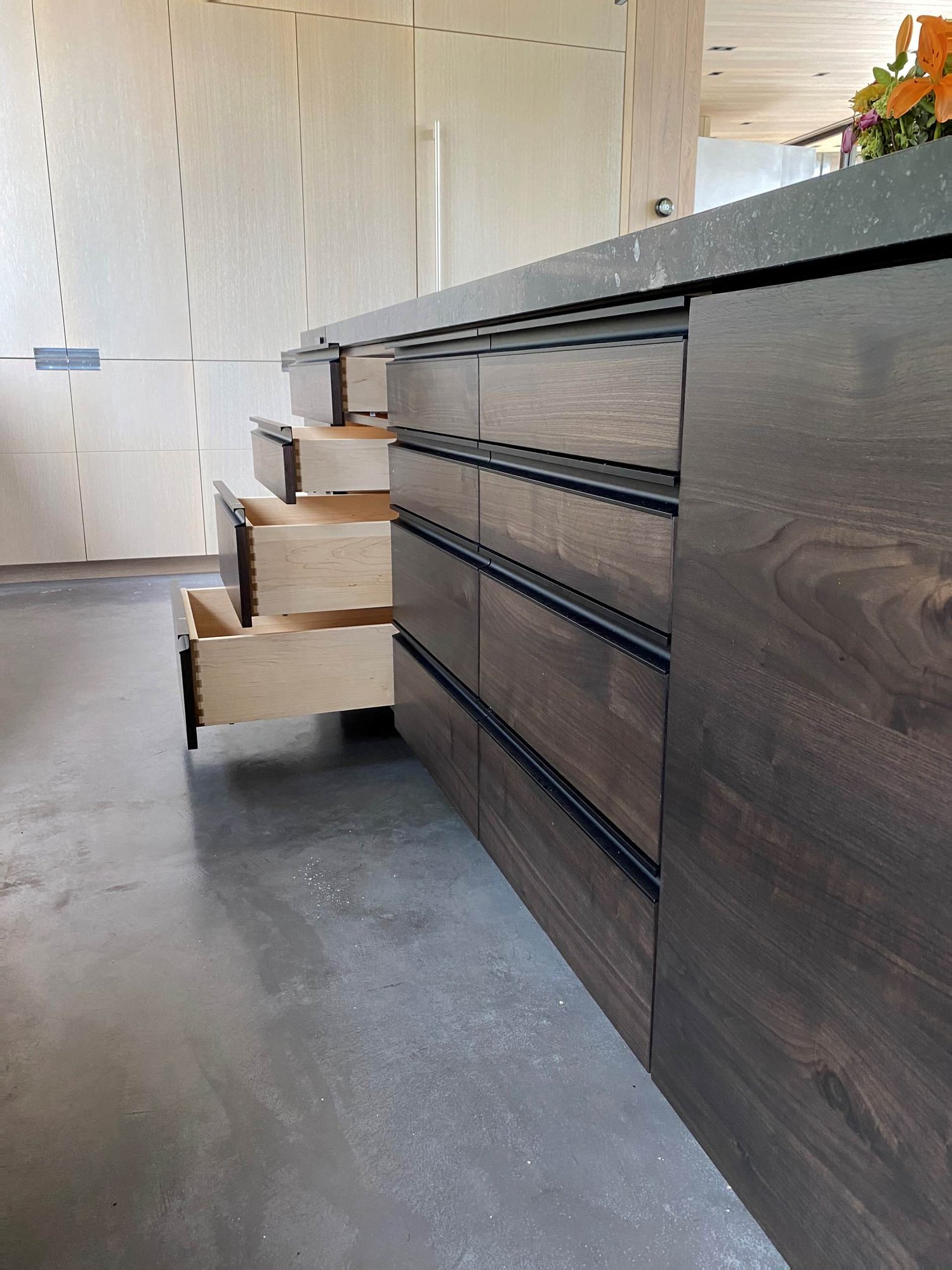 Large trendy u-shaped concrete floor, gray floor and wood ceiling open concept kitchen with an undermount sink, flat-panel cabinets, light wood cabinets, yellow backsplash, glass sheet backsplash, paneled appliances, an island and gray countertops, by Jensen Design in Telluride, CO