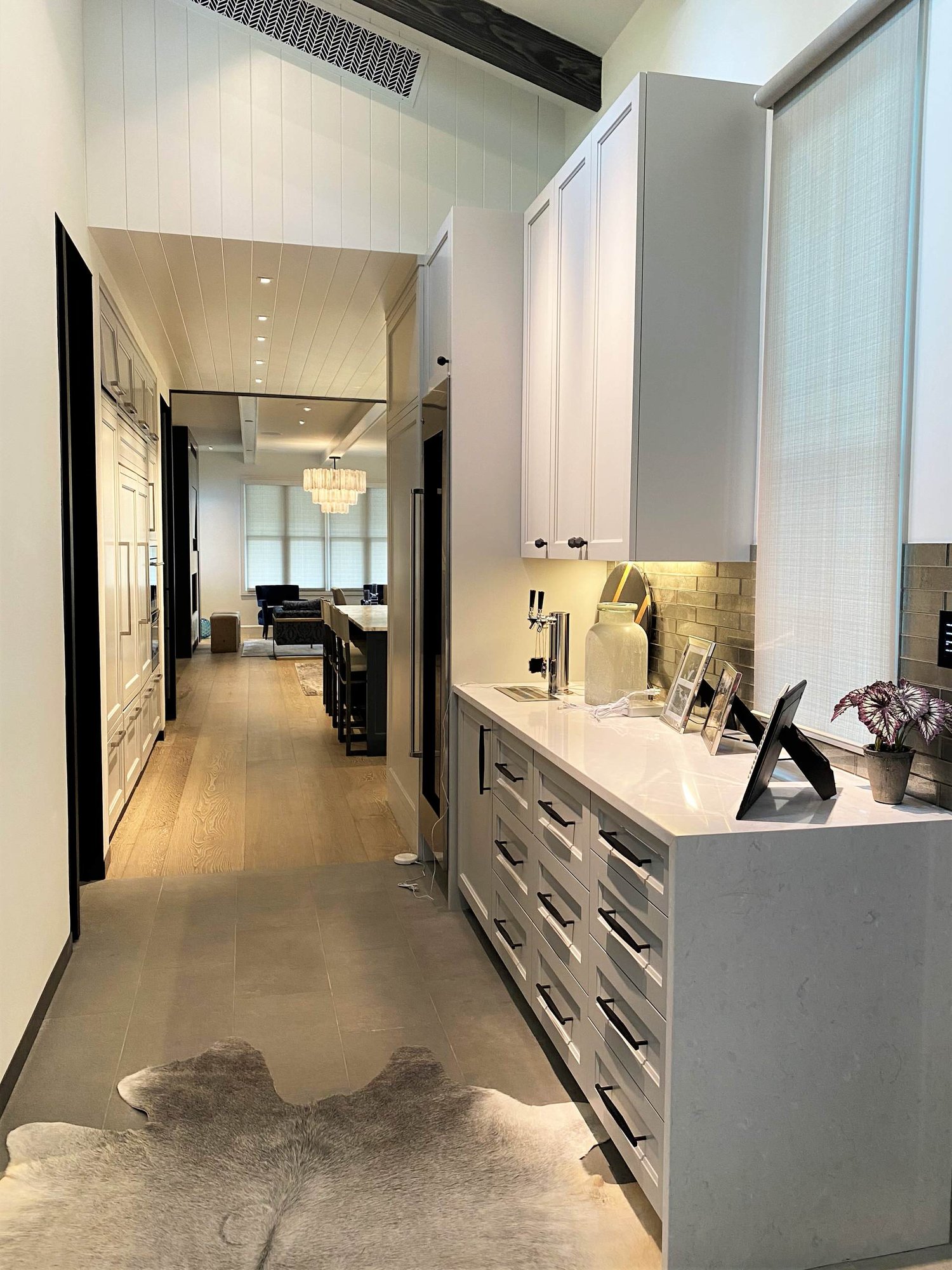 Large contemporary u-shaped light wood floor, brown floor and shiplap ceiling open concept kitchen with an undermount sink, recessed-panel cabinets, white cabinets, gray backsplash, paneled appliances, an island and white countertops, by Jensen Design in Telluride, CO