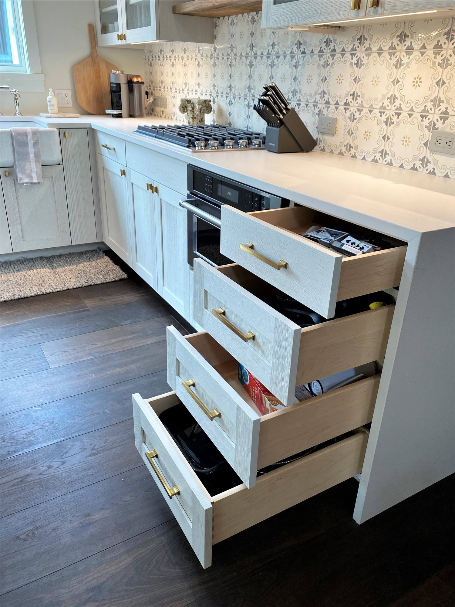 Mid-sized contemporary l-shaped dark wood floor, brown floor and vaulted ceiling open concept kitchen with a farmhouse sink, recessed-panel cabinets, white cabinets, white backsplash, paneled appliances and an island, by Jensen Design in Telluride, CO