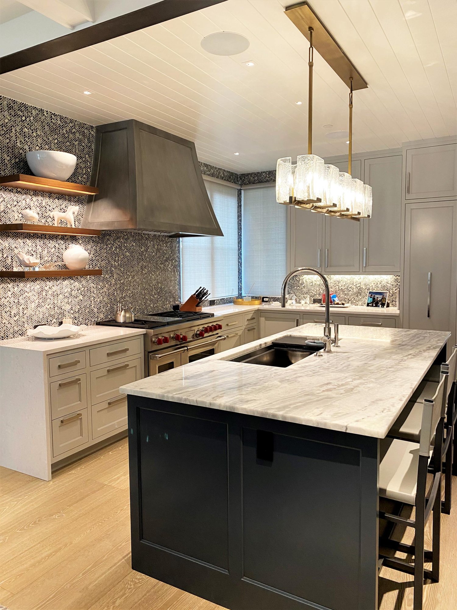 Large contemporary u-shaped light wood floor, brown floor and shiplap ceiling open concept kitchen with an undermount sink, recessed-panel cabinets, white cabinets, gray backsplash, paneled appliances, an island and white countertops, by Jensen Design in Telluride, CO
