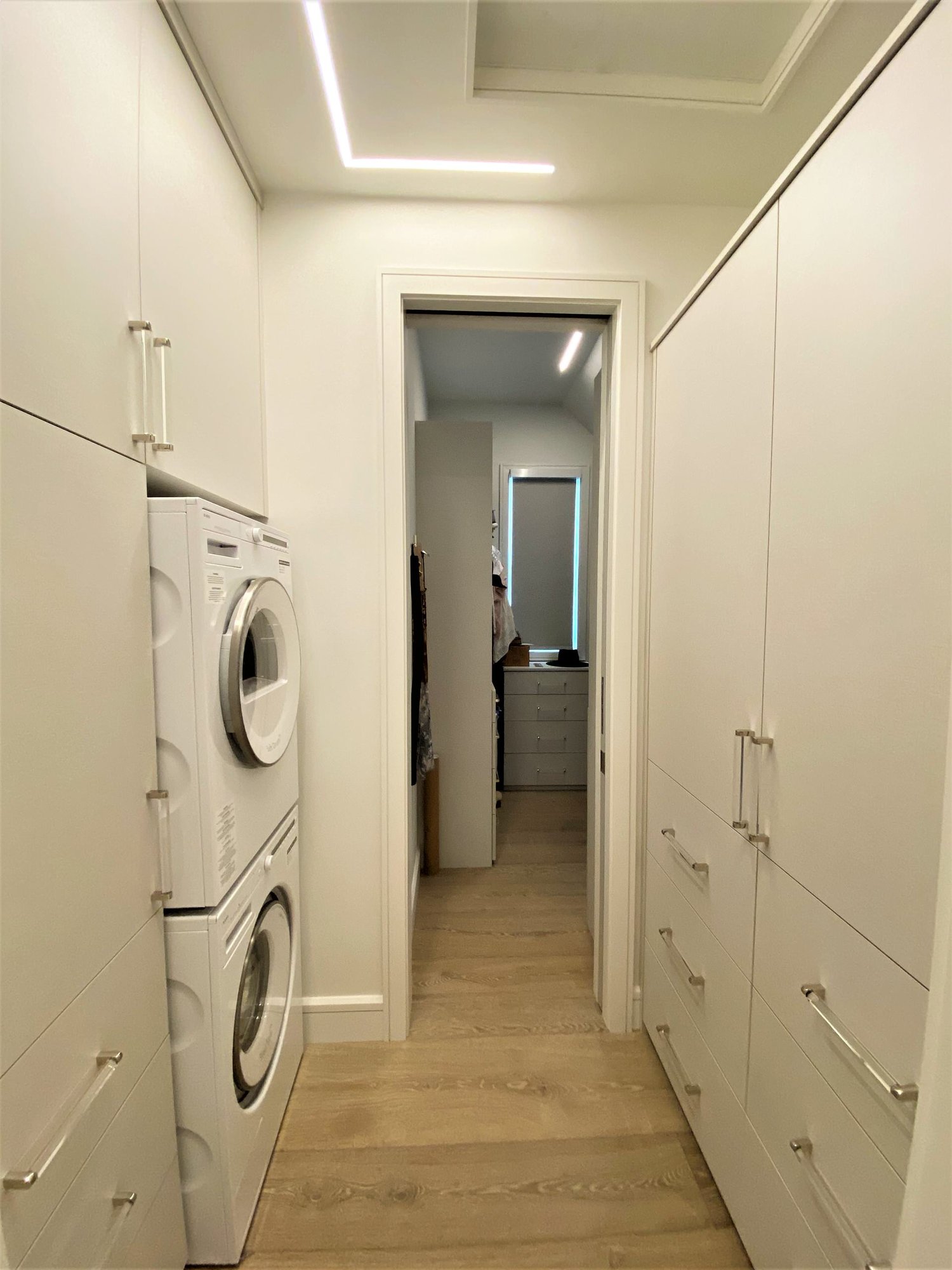 Mid-sized contemporary gender-neutral medium tone wood floor and brown floor walk-in closet with flat-panel cabinets and white cabinets, by Jensen Design in Telluride, CO
