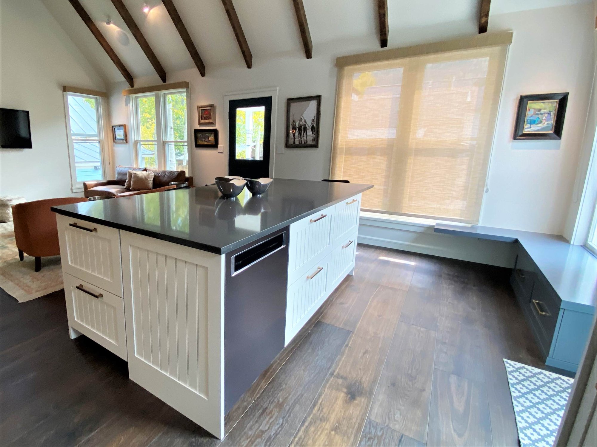 Mid-sized contemporary l-shaped dark wood floor, brown floor and vaulted ceiling open concept kitchen with a farmhouse sink, recessed-panel cabinets, white cabinets, white backsplash, paneled appliances and an island, by Jensen Design in Telluride, CO