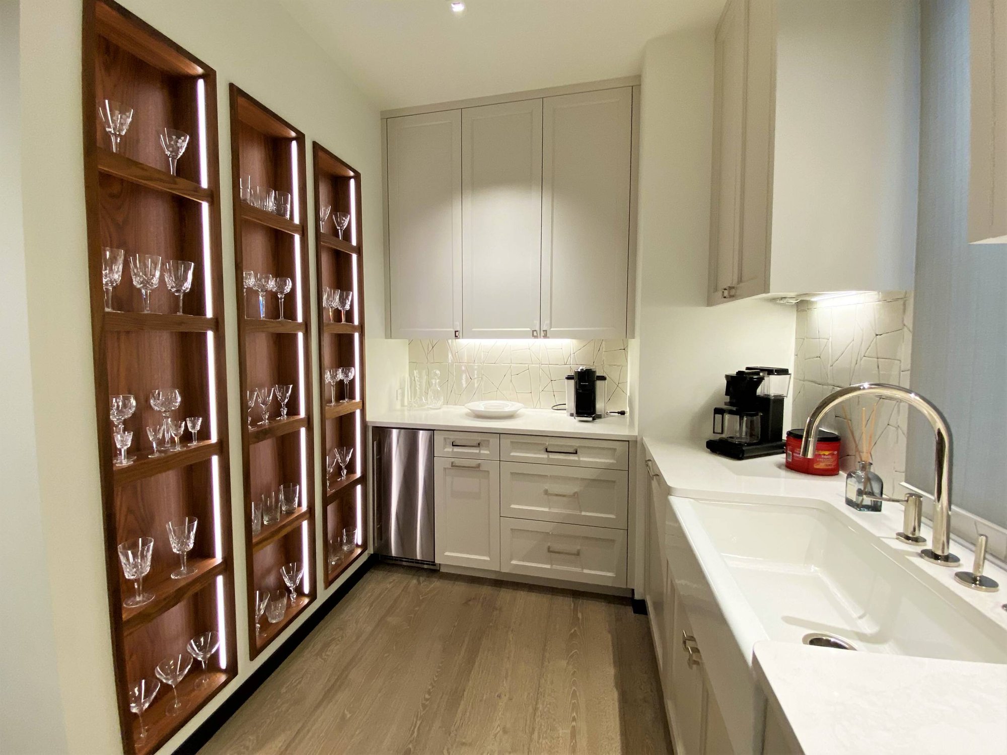 Mid-sized contemporary u-shaped light wood floor kitchen pantry with recessed-panel cabinets, white cabinets, white countertops, a farmhouse sink, white backsplash and stainless steel appliances, by Jensen Design in Telluride, CO