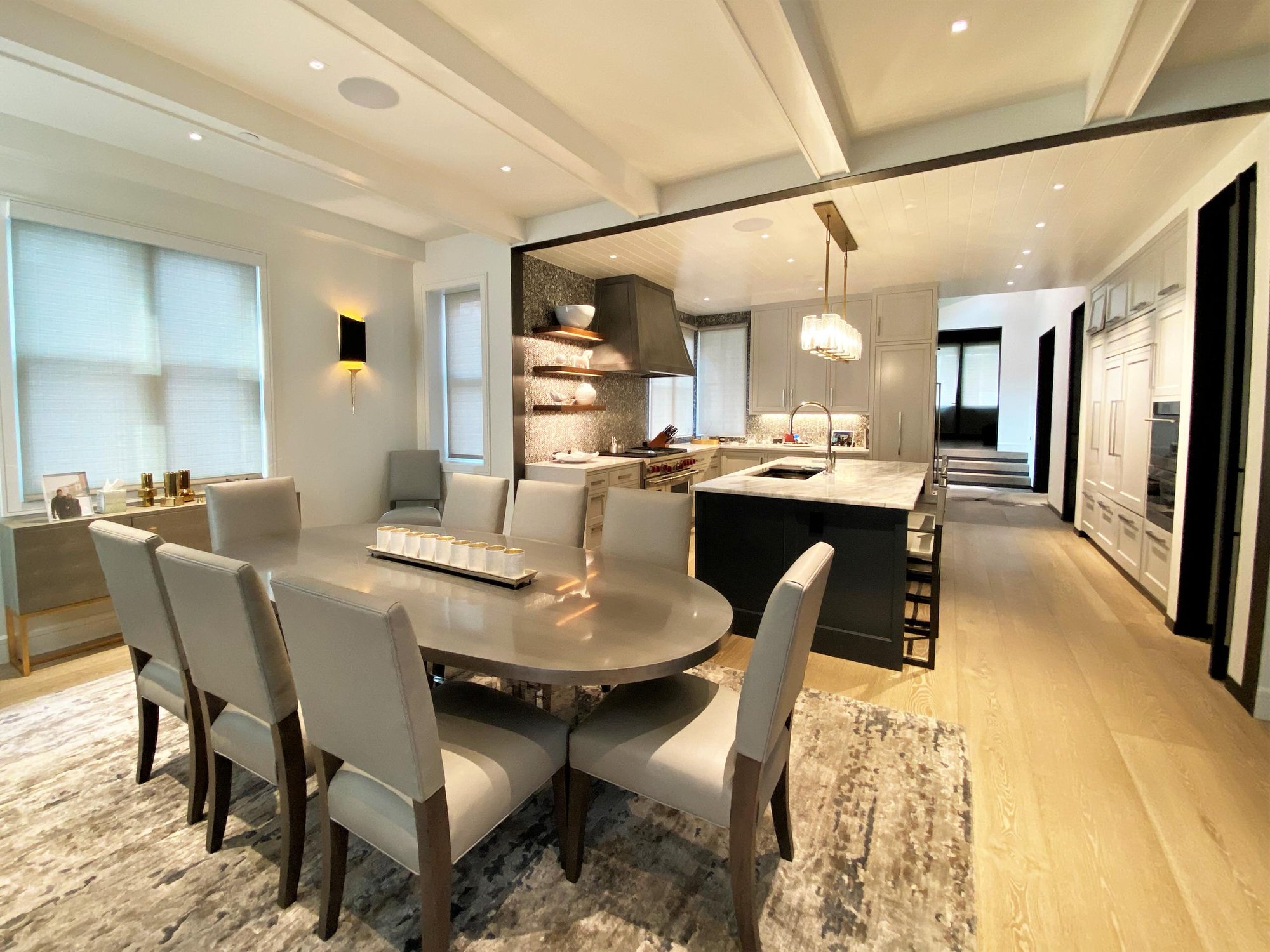 Large trendy u-shaped light wood floor, brown floor and shiplap ceiling open concept kitchen with an undermount sink, recessed-panel cabinets, white cabinets, gray backsplash, paneled appliances, an island and white countertops, by Jensen Design in Telluride, CO