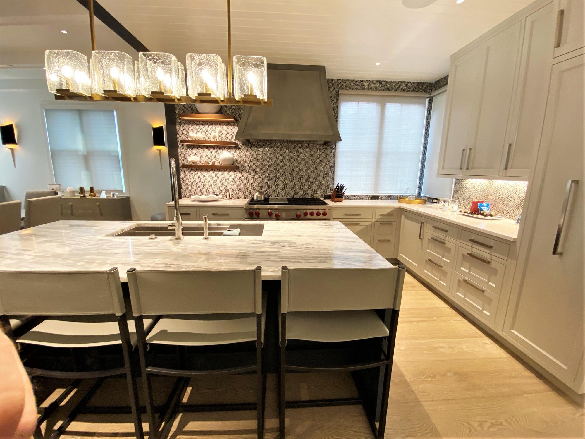 Large trendy u-shaped light wood floor, brown floor and shiplap ceiling open concept kitchen with an undermount sink, recessed-panel cabinets, white cabinets, gray backsplash, paneled appliances, an island and white countertops, by Jensen Design in Telluride, CO