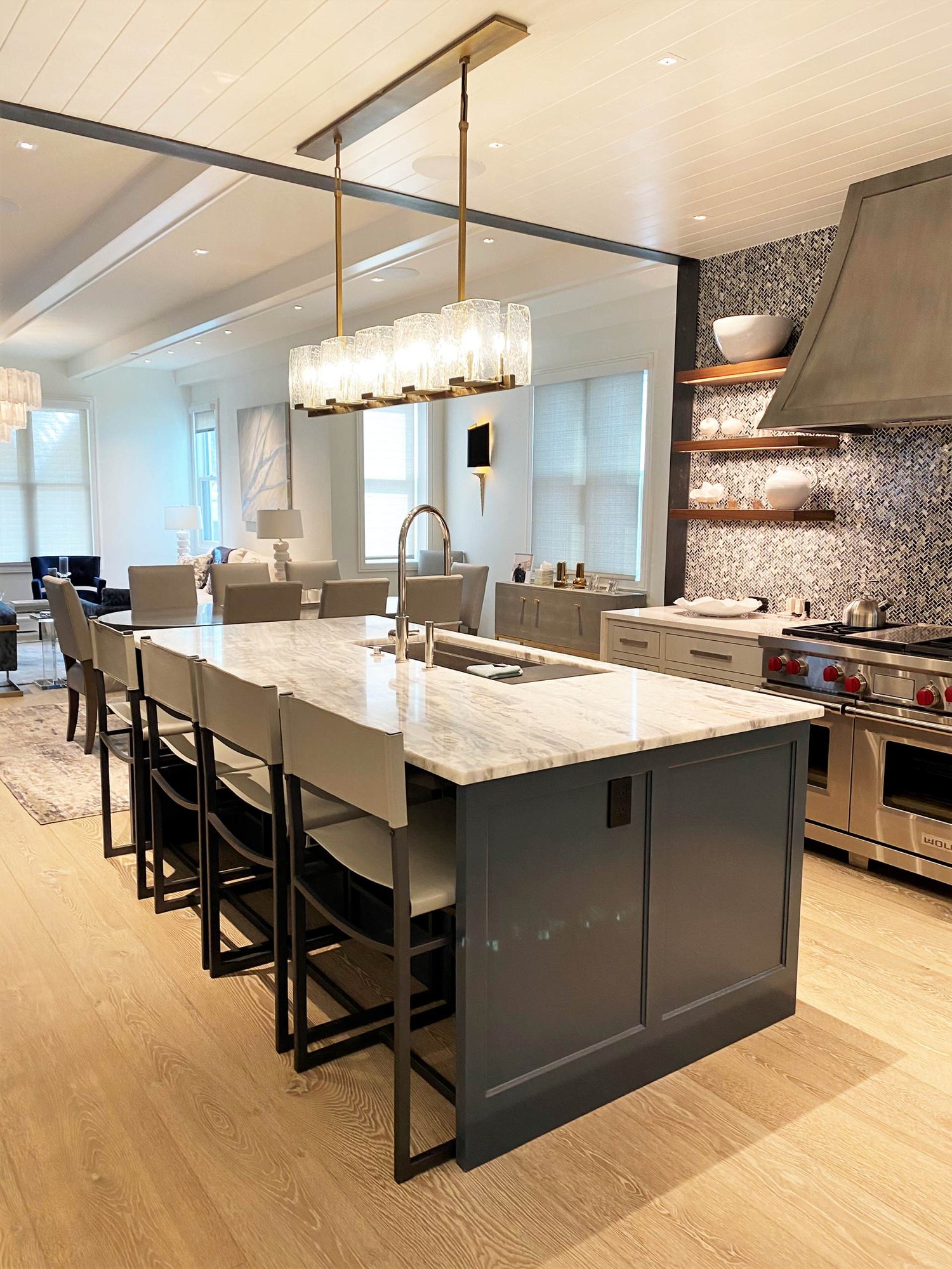 Large trendy u-shaped light wood floor, brown floor and shiplap ceiling open concept kitchen with an undermount sink, recessed-panel cabinets, white cabinets, gray backsplash, paneled appliances, an island and white countertops, by Jensen Design in Telluride, CO