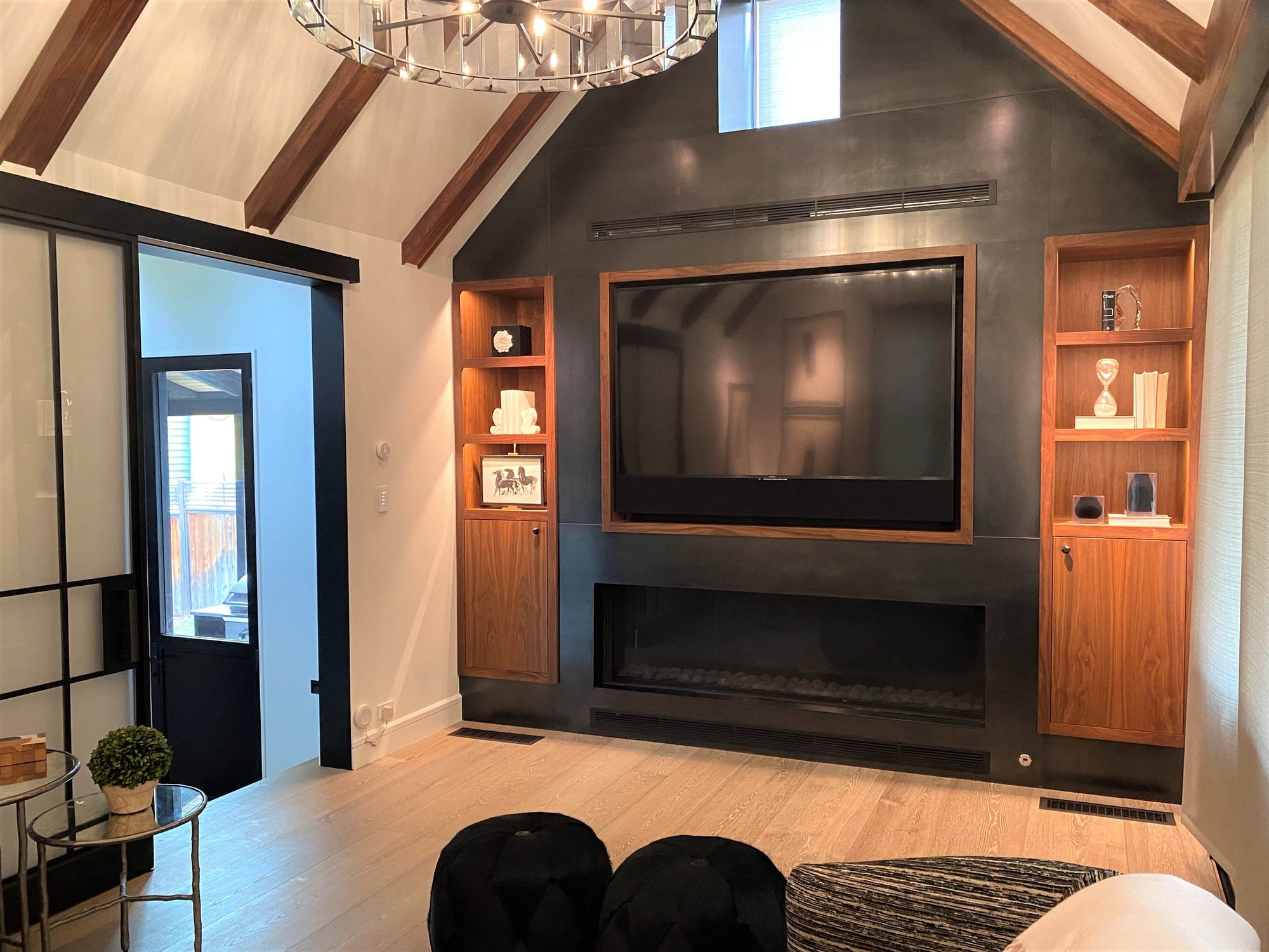 Mid-sized contemporary enclosed light wood floor and vaulted ceiling family room with black walls, a ribbon fireplace, a metal fireplace and a media wall, by Jensen Design in Telluride, CO