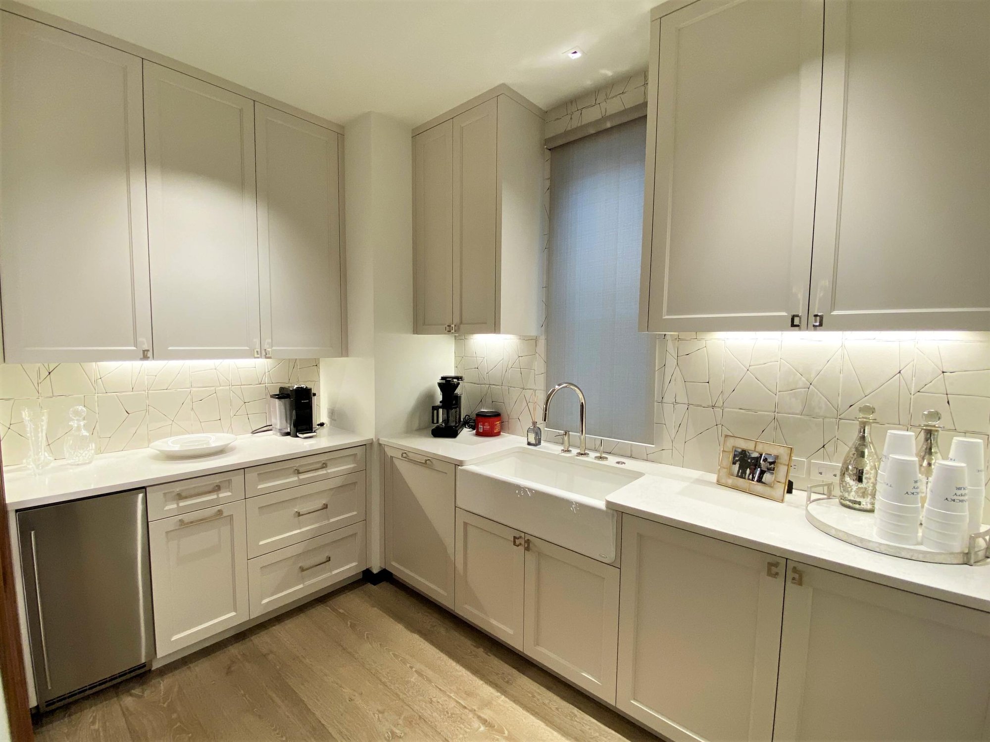 Mid-sized contemporary u-shaped light wood floor kitchen pantry with a farmhouse sink, recessed-panel cabinets, white cabinets, white backsplash, stainless steel appliances and white countertops, by Jensen Design in Telluride, CO