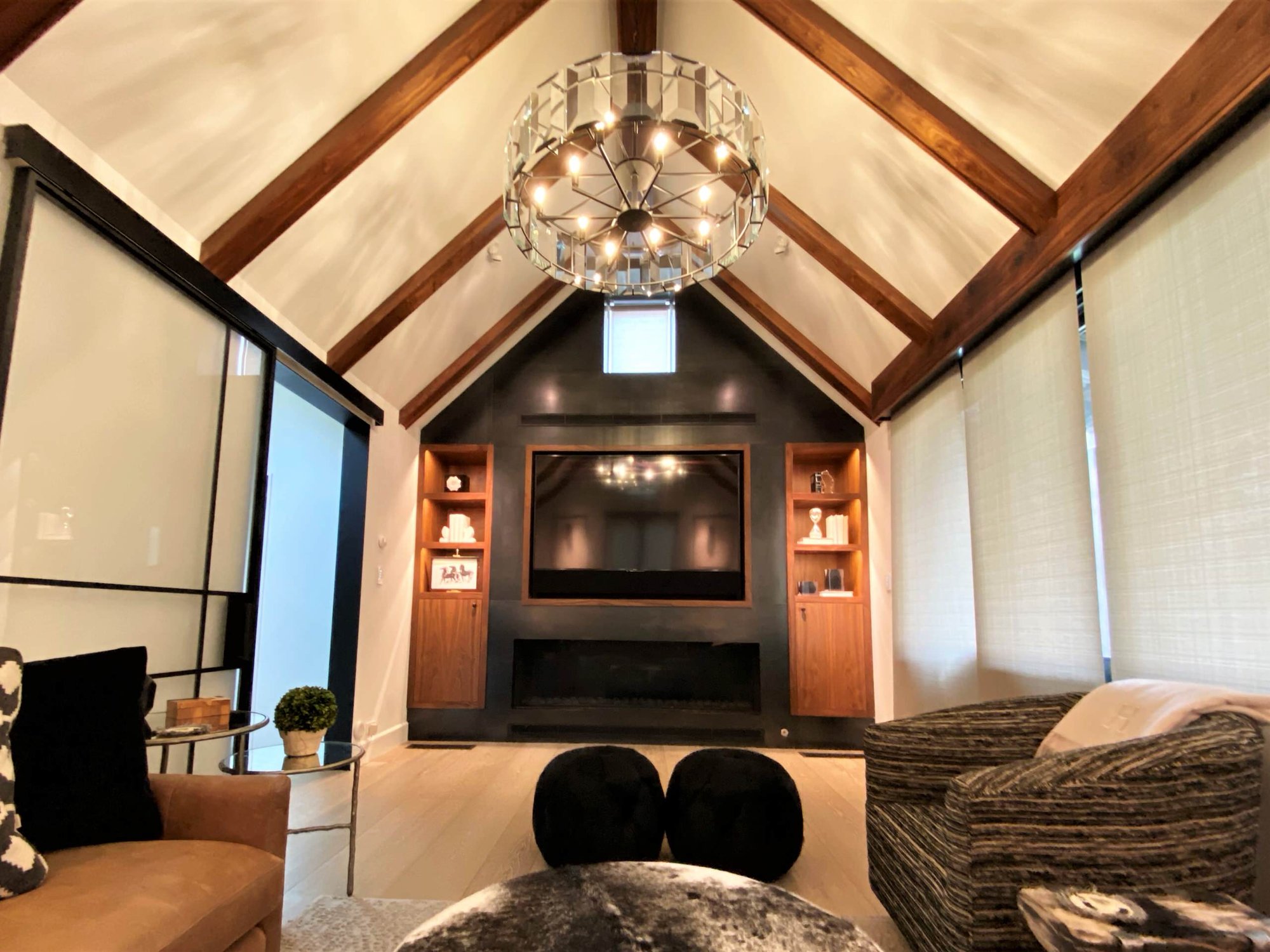 Mid-sized trendy enclosed light wood floor and vaulted ceiling family room with black walls, a ribbon fireplace, a metal fireplace and a media wall, by Jensen Design in Telluride, CO
