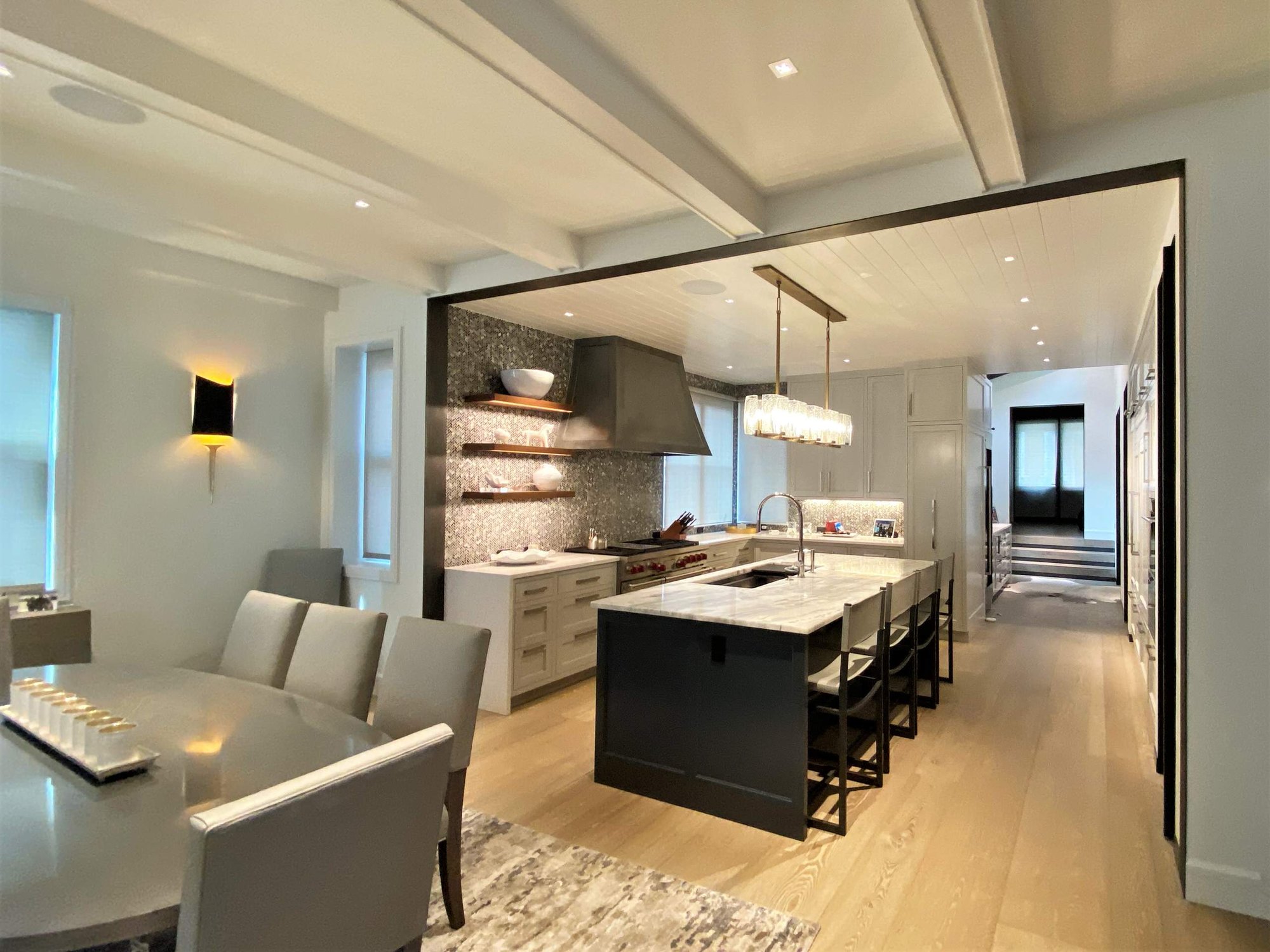 Large trendy u-shaped light wood floor, brown floor and shiplap ceiling open concept kitchen with an undermount sink, recessed-panel cabinets, white cabinets, gray backsplash, paneled appliances, an island and white countertops, by Jensen Design in Telluride, CO