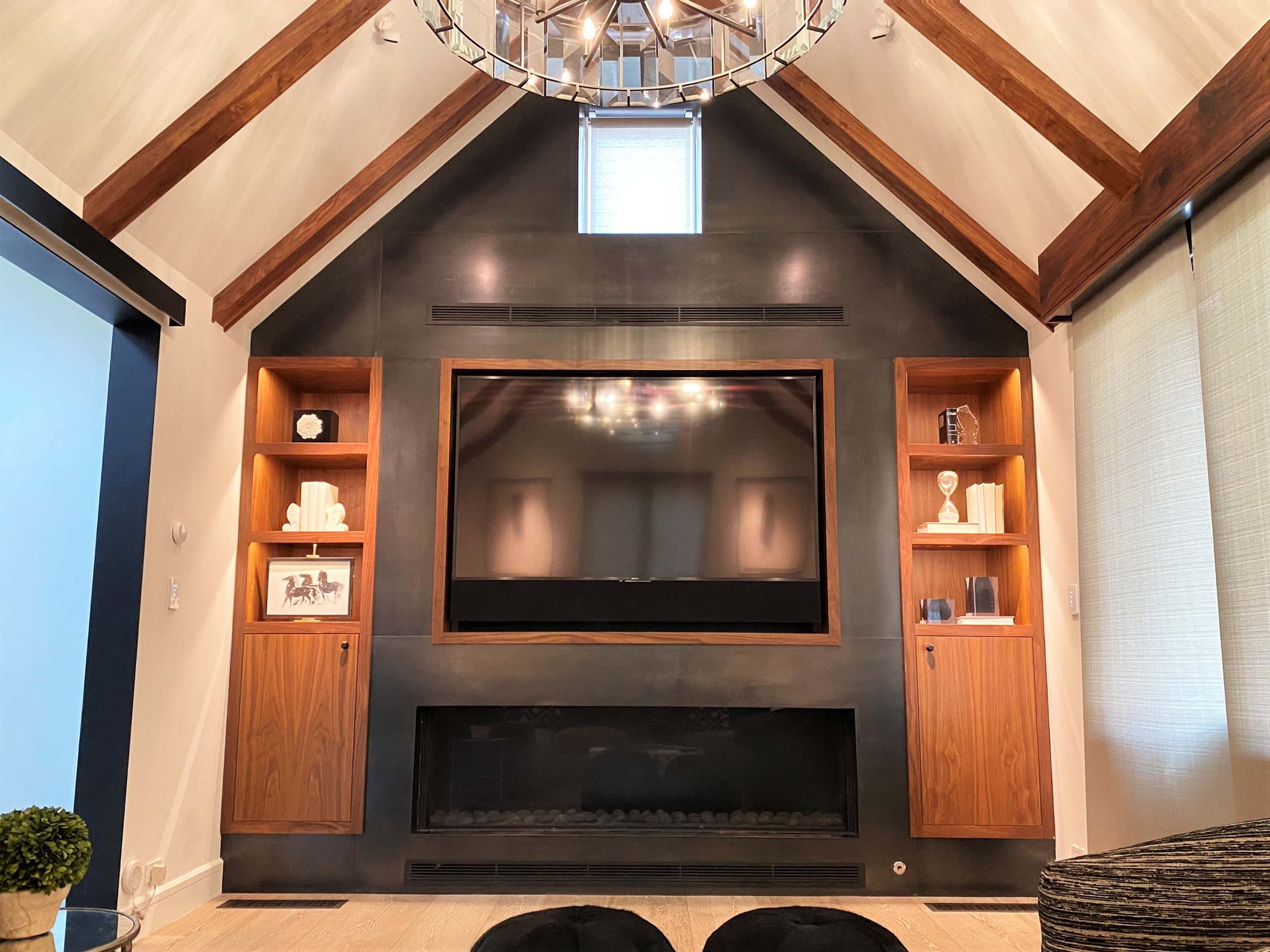 Mid-sized trendy enclosed light wood floor and vaulted ceiling family room with black walls, a ribbon fireplace, a metal fireplace and a media wall, by Jensen Design in Telluride, CO