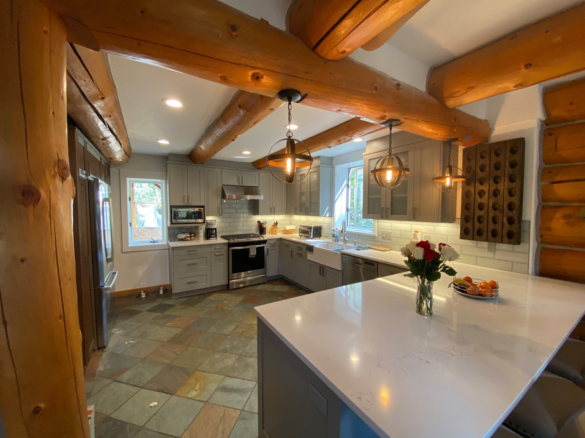Mid-sized contemporary u-shaped green floor and exposed beam kitchen pantry with a farmhouse sink, shaker cabinets, gray cabinets, gray backsplash, stainless steel appliances and white countertops, by Jensen Design in Telluride, CO