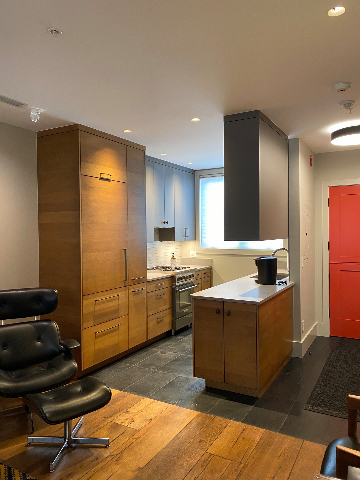 Small mid-century modern u-shaped open concept kitchen with flat-panel cabinets, medium tone wood cabinets, concrete countertops, white backsplash, stainless steel appliances and white countertops, by Jensen Design in Telluride, CO