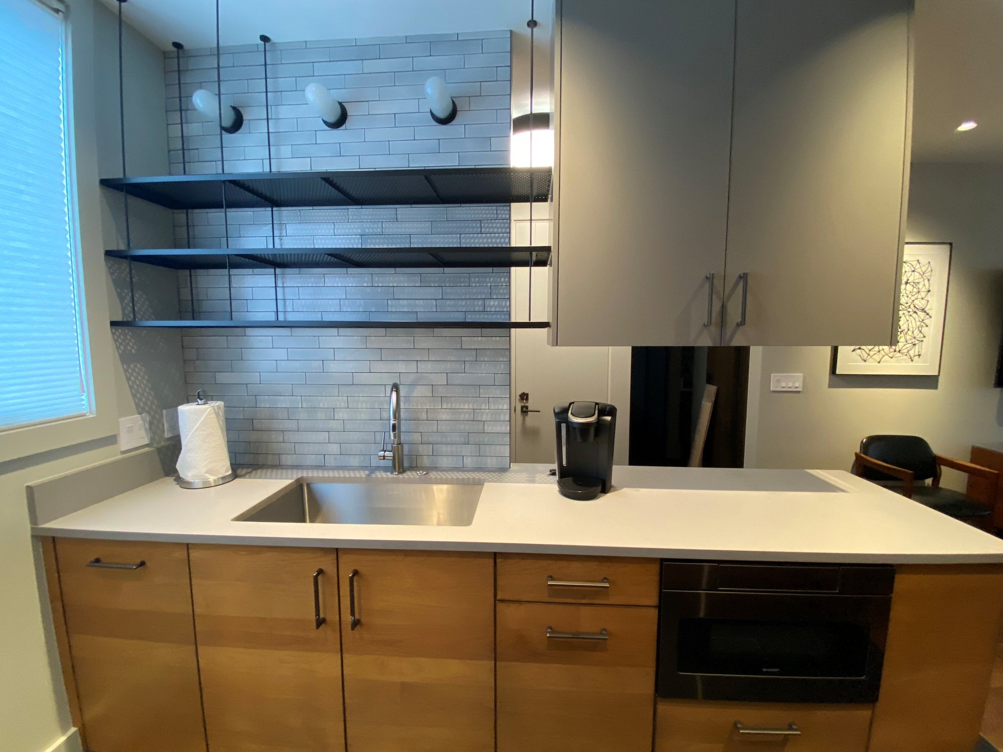 Small 1950s u-shaped open concept kitchen with an undermount sink, flat-panel cabinets, medium tone wood cabinets, concrete countertops, white backsplash, stainless steel appliances and white countertops, by Jensen Design in Telluride, CO