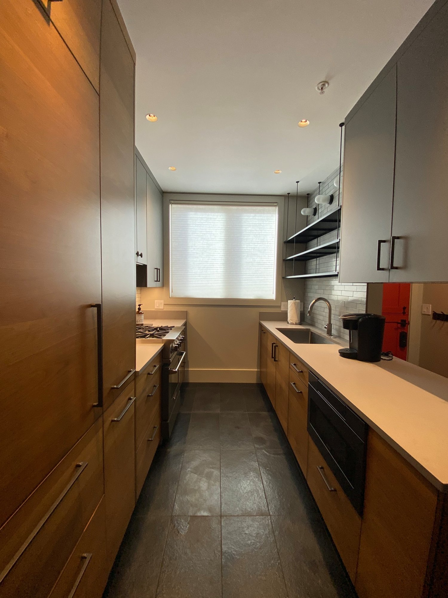 Small 1950s u-shaped black floor open concept kitchen with an undermount sink, flat-panel cabinets, medium tone wood cabinets, concrete countertops, white backsplash, stainless steel appliances and white countertops, by Jensen Design in Telluride, CO