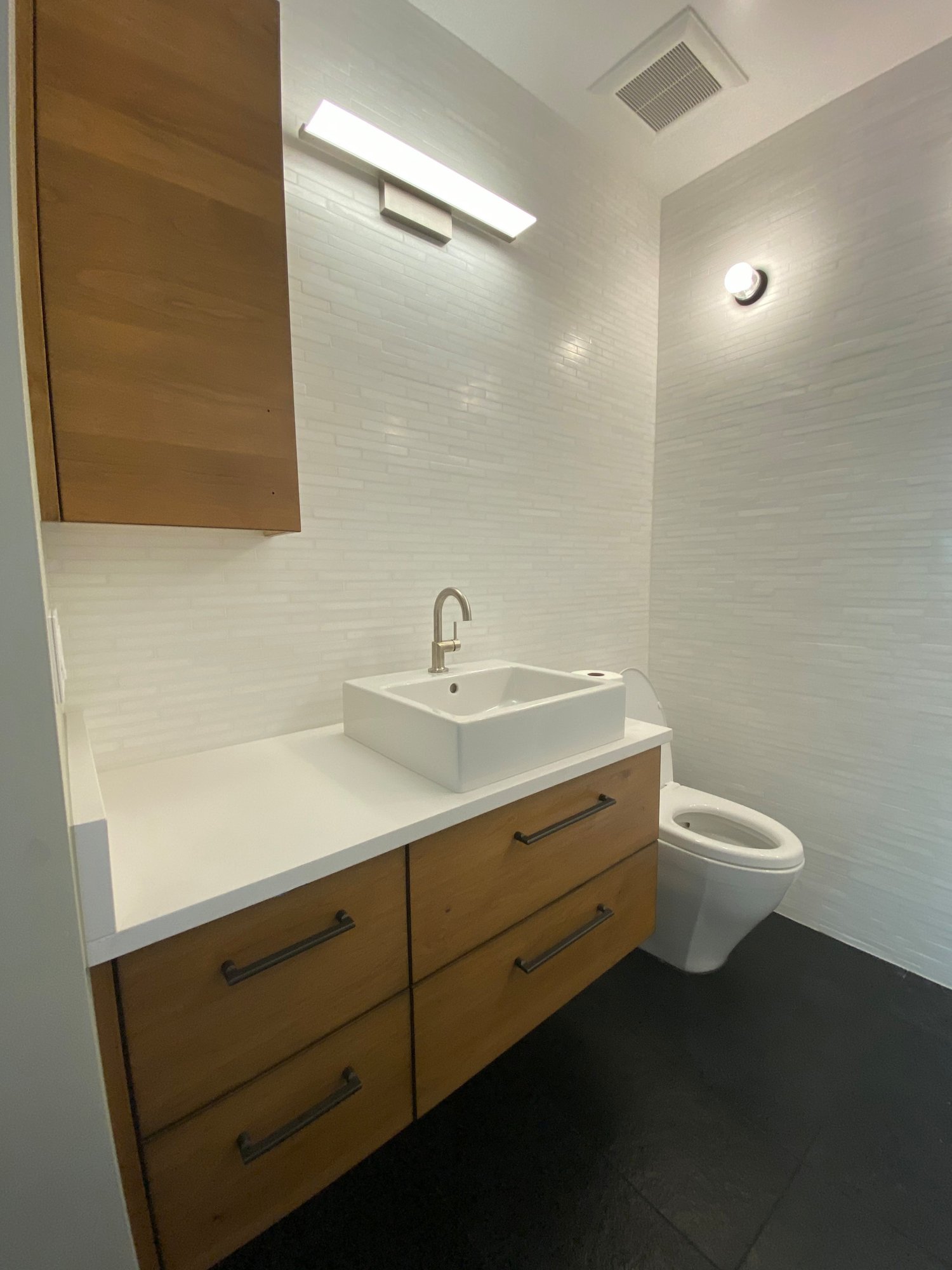 Small mid-century modern kids' black floor and single-sink bathroom with flat-panel cabinets, medium tone wood cabinets, beige walls, a vessel sink, white countertops and a floating vanity, by Jensen Design in Telluride, CO