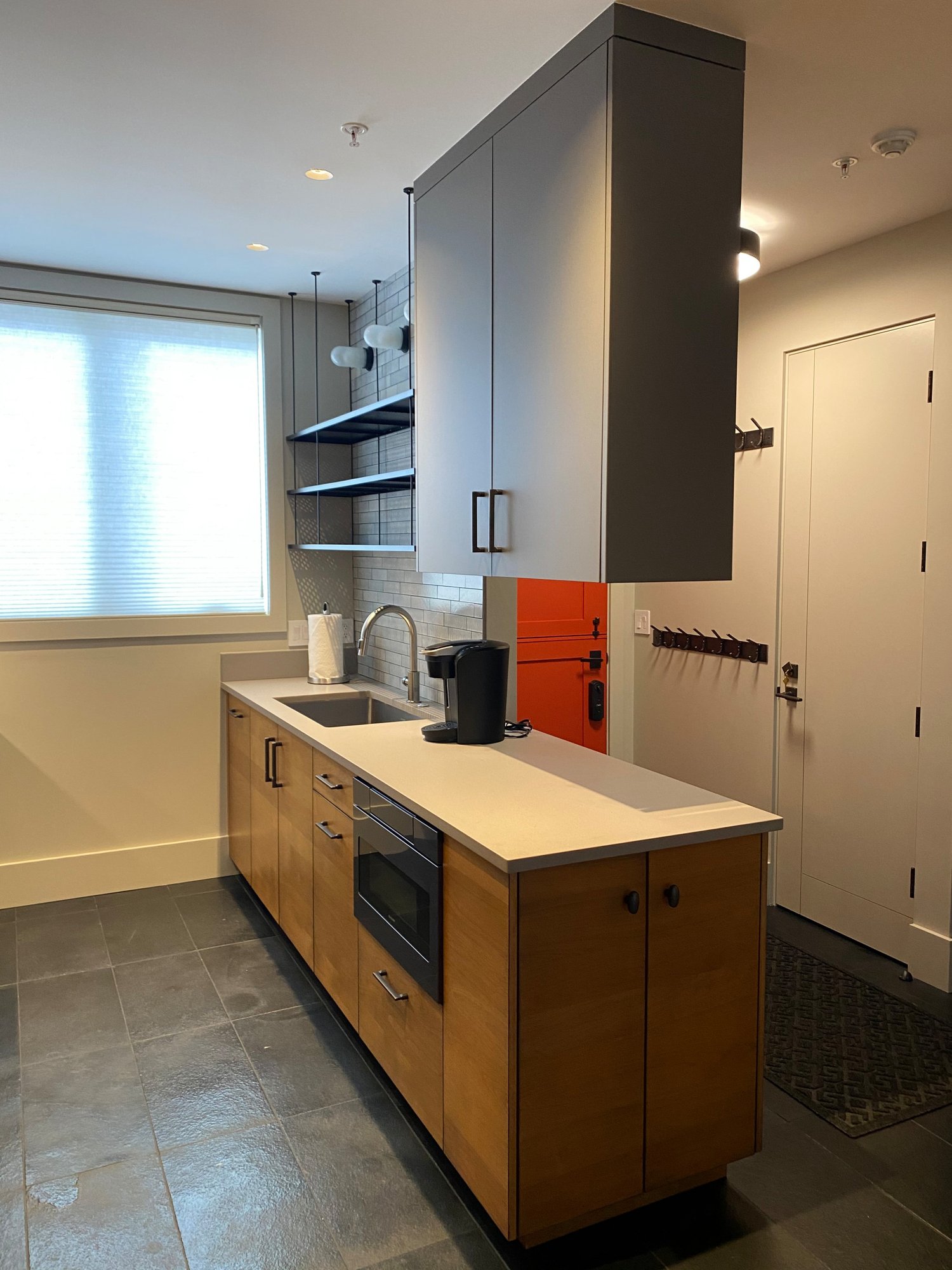 Small 1960s u-shaped open concept kitchen with flat-panel cabinets, medium tone wood cabinets, concrete countertops, white backsplash, stainless steel appliances and white countertops, by Jensen Design in Telluride, CO