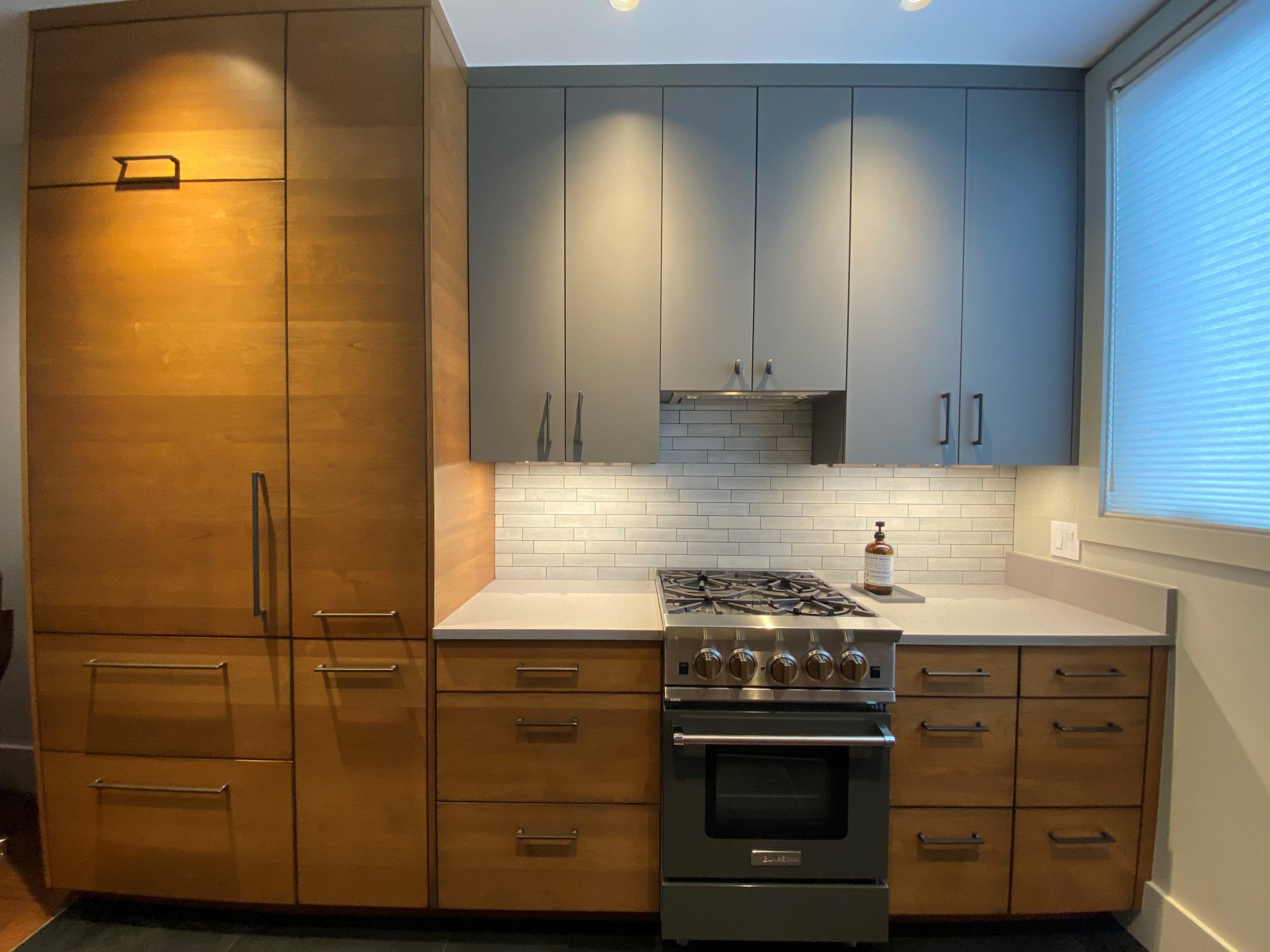 Small mid-century modern u-shaped open concept kitchen with flat-panel cabinets, medium tone wood cabinets, concrete countertops, white backsplash, stainless steel appliances and white countertops, by Jensen Design in Telluride, CO