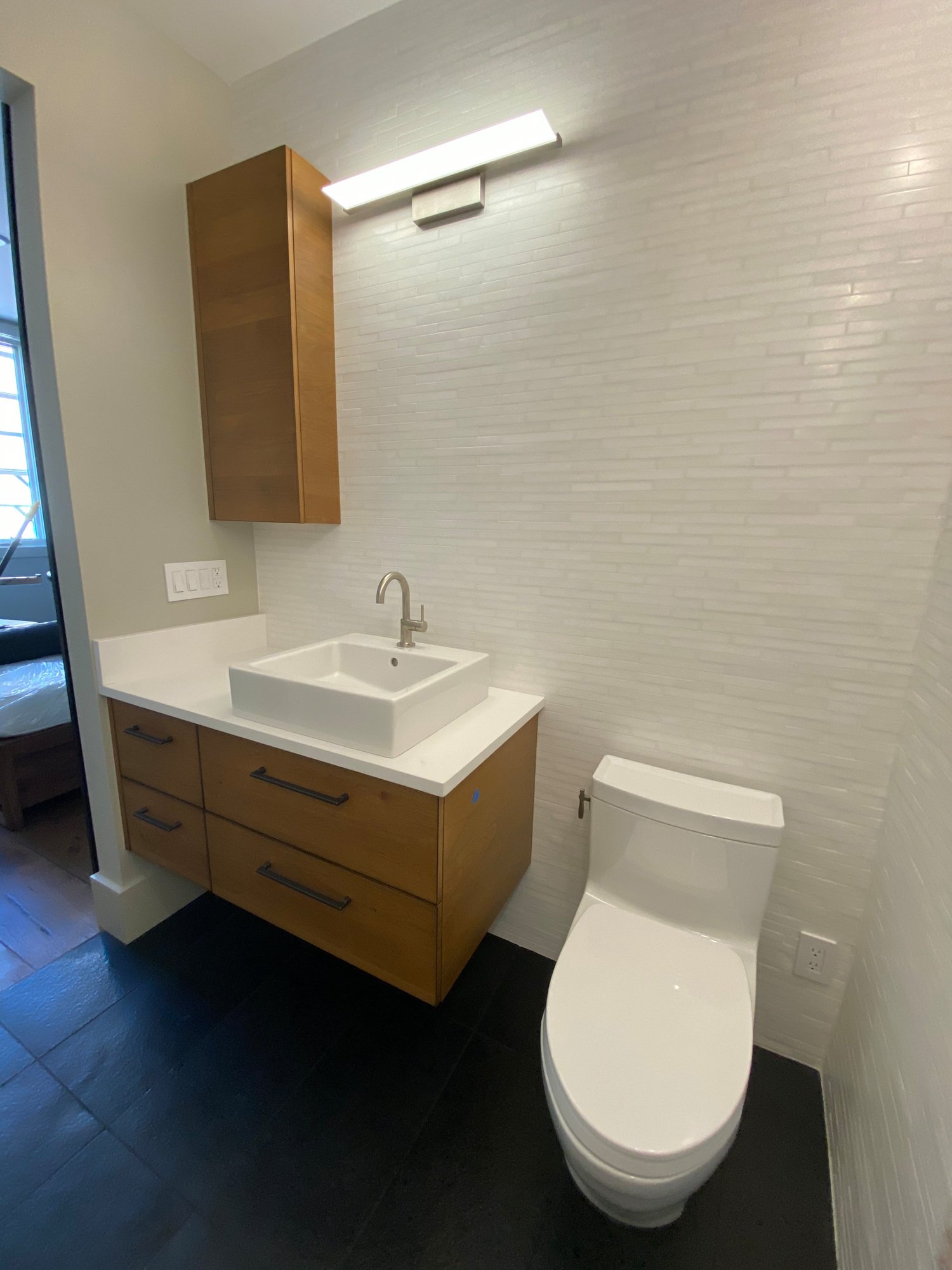 Small 1960s kids' black floor and single-sink bathroom with flat-panel cabinets, medium tone wood cabinets, beige walls, a vessel sink, white countertops and a floating vanity, by Jensen Design in Telluride, CO