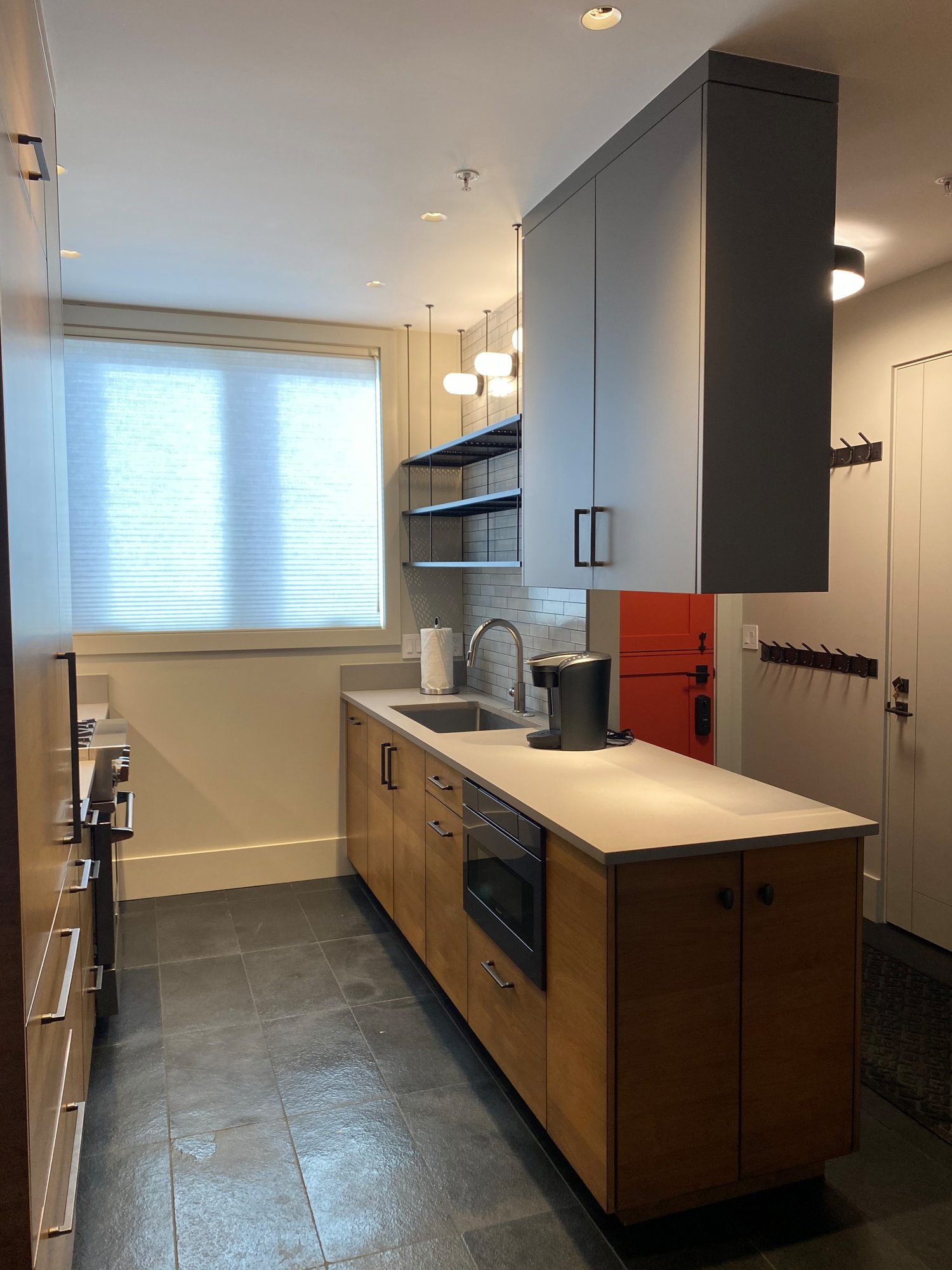 Small 1960s u-shaped black floor open concept kitchen with an undermount sink, flat-panel cabinets, medium tone wood cabinets, concrete countertops, white backsplash, stainless steel appliances and white countertops, by Jensen Design in Telluride, CO